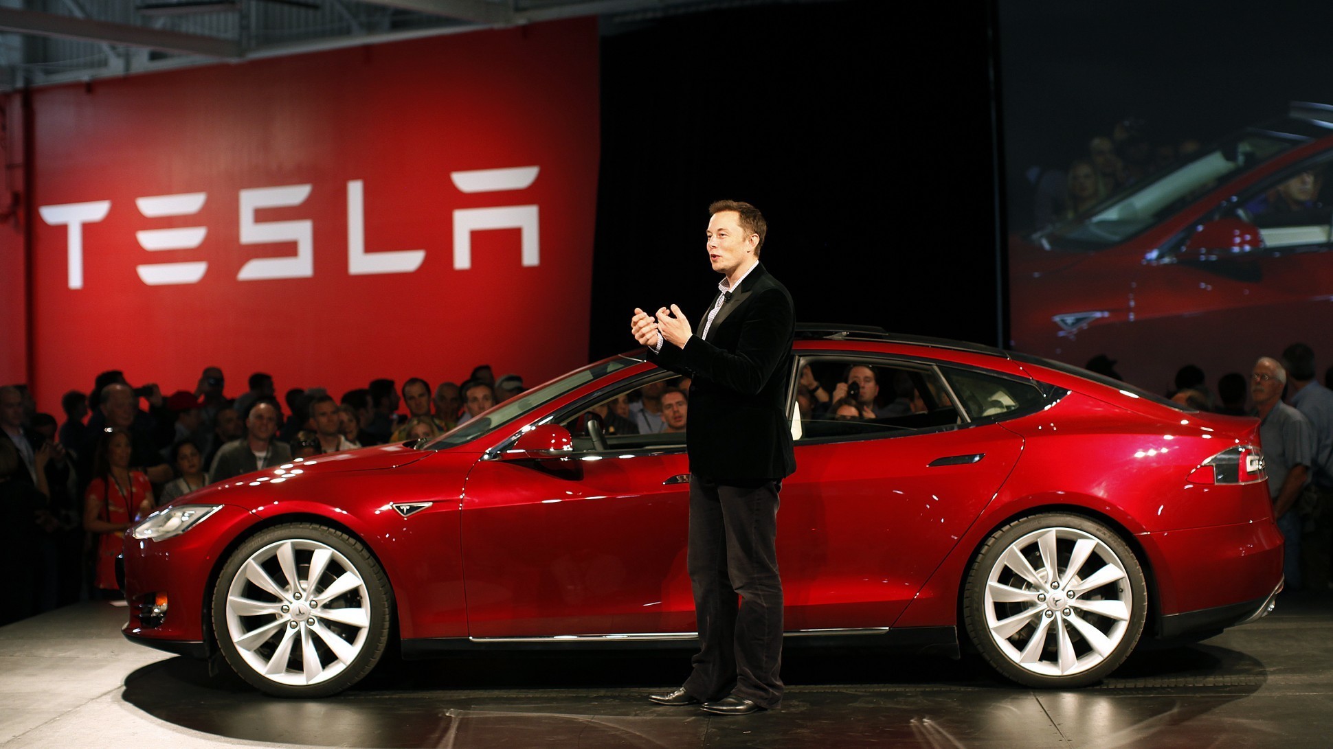 Elon Musk standing next to a Tesla Model S at a Press Event.