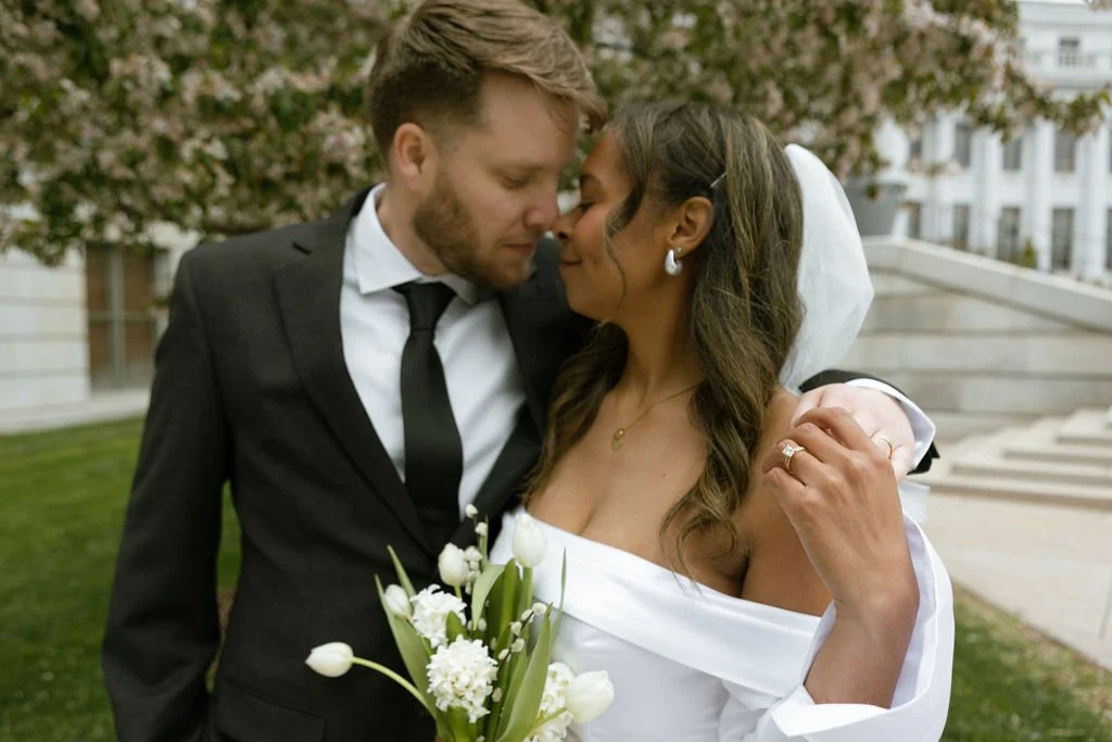 Romantic embrace between bride and groom under the cherry blossoms at the Denver courthouse.