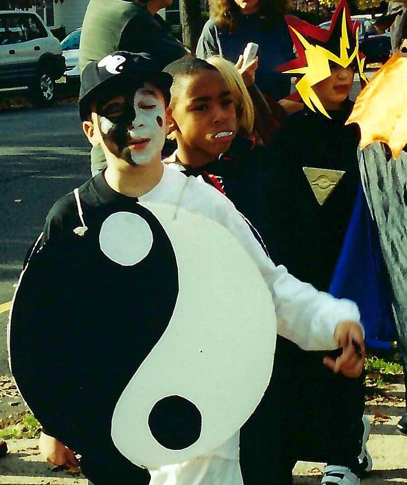  Sam dressed up as a yin-yang sign. Other kids in other costumes are seen in the background. 