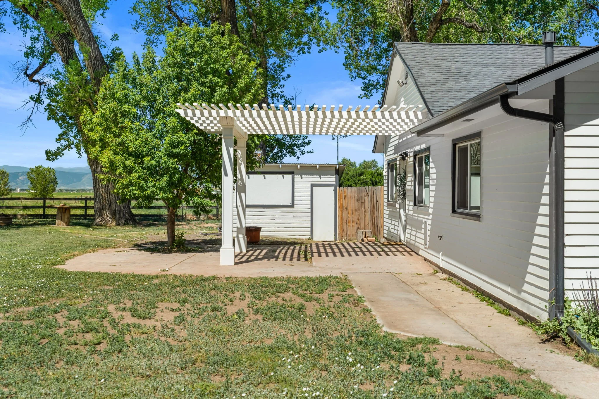 The shed behind the pergola features a TV behind the dropdown window for outdoor entertainment