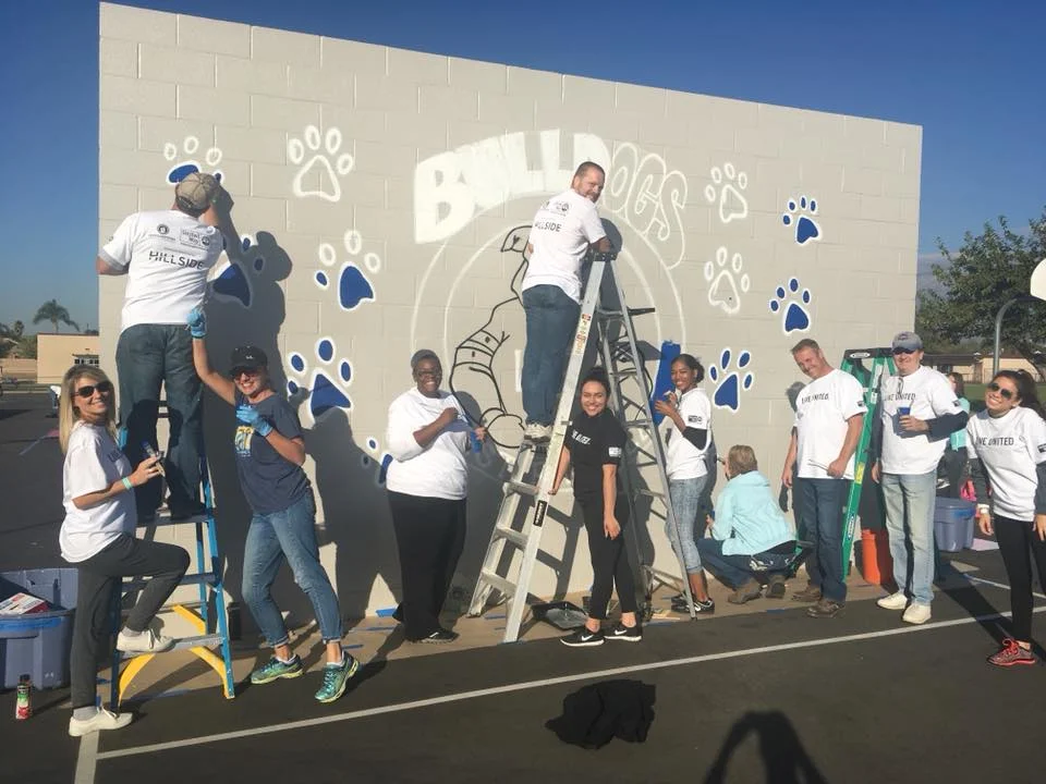 Volunteers work to complete the mural on the West Randall Elementary Playground, led by IEUW Americorps, Carly Corona. photo courtesy of IEUW