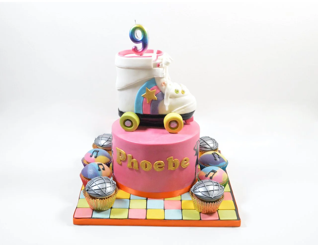 A pink cake with a sculpture of a rollerskate on top for a 9th birthday. The party was disco themed