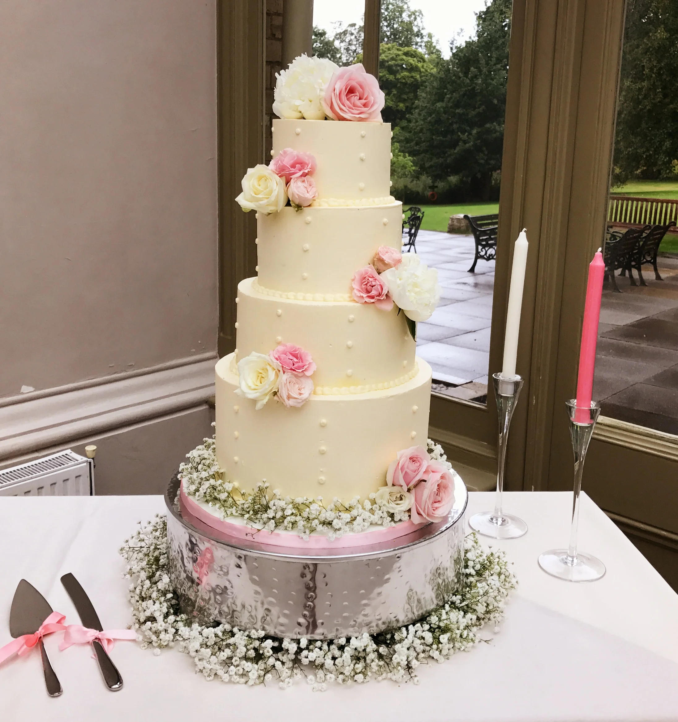 4 tier buttercream wedding cake lightly decorated with fresh pink and cream roses