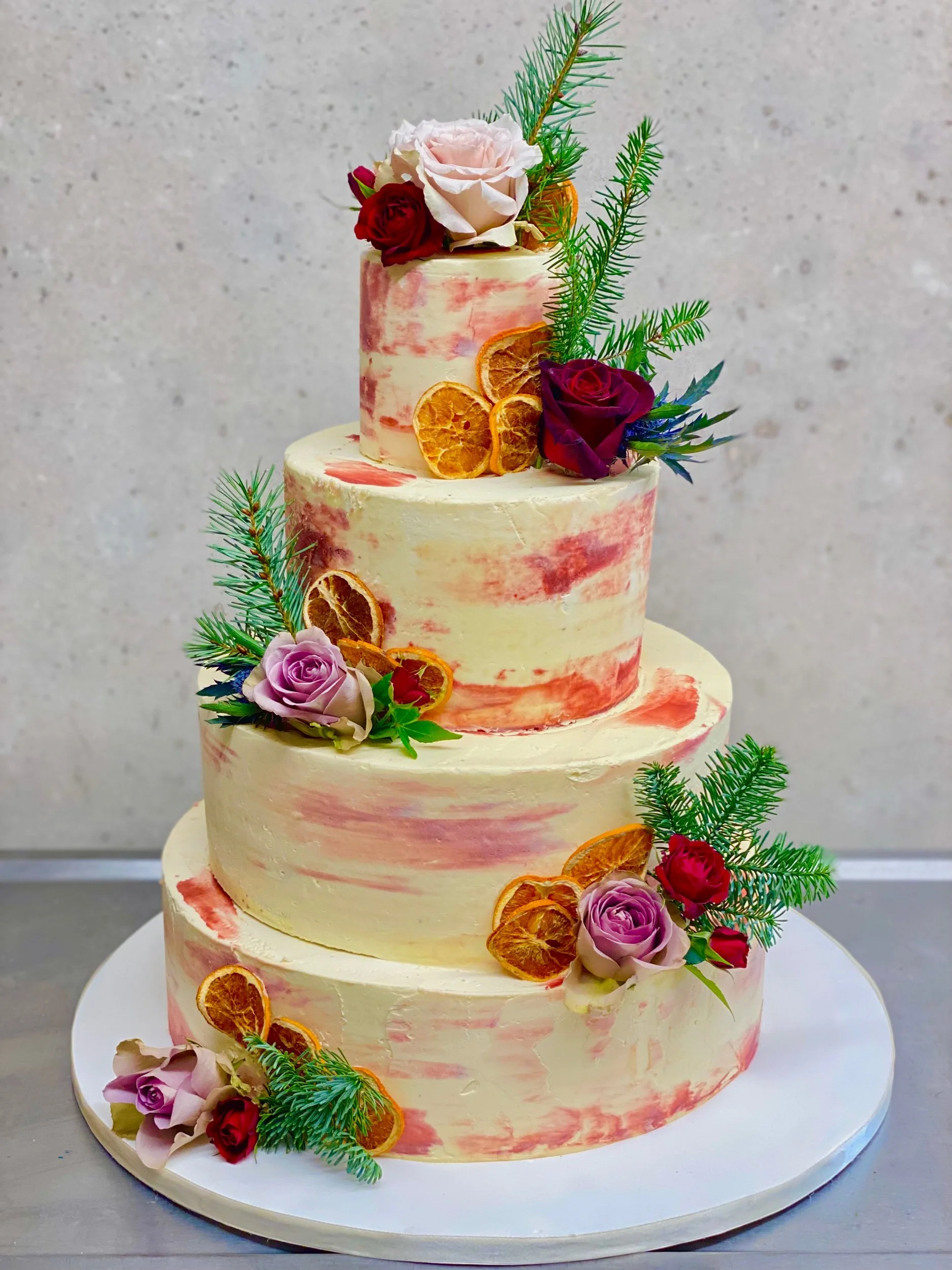A 4 tier buttercream wedding cake with watercolour effect, dried fruits and fresh flowers