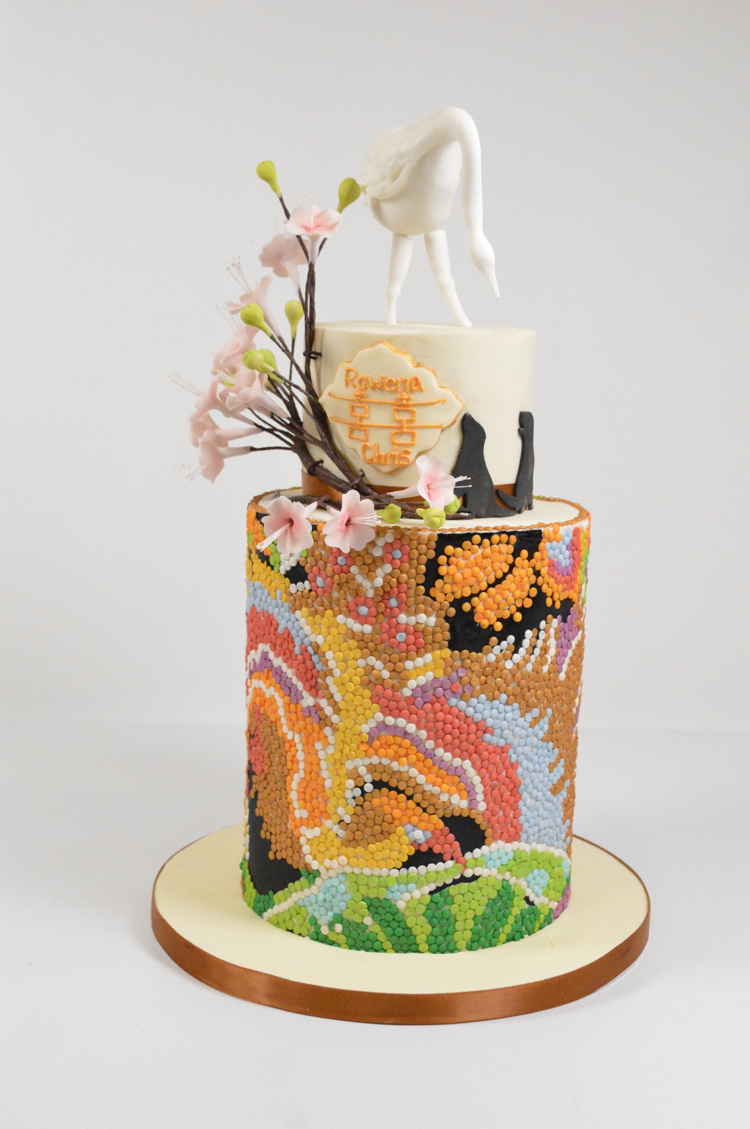 2 tier wedding cake hand decorated with sequins, sugar flower blossoms and cranes
