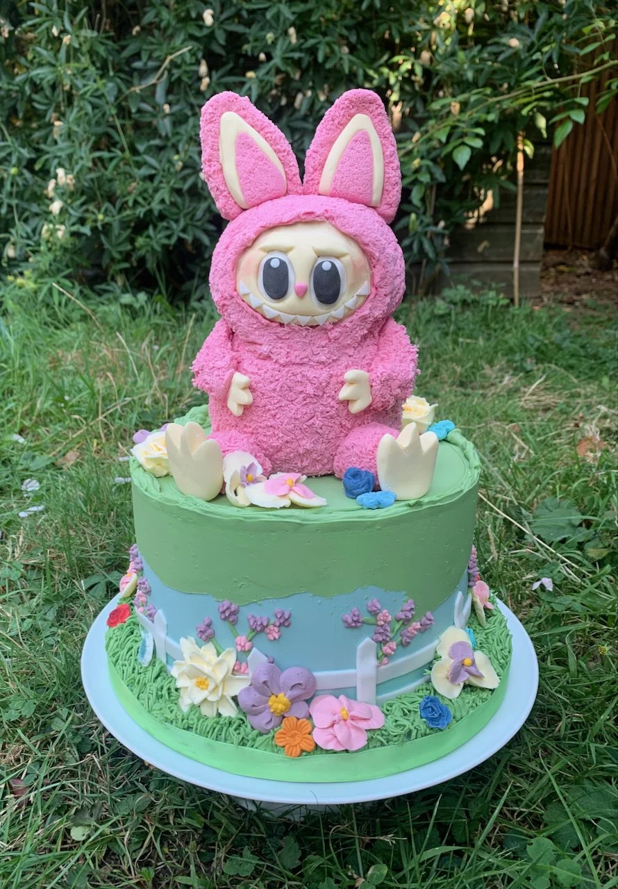 Pink Labubu cake sitting on a garden