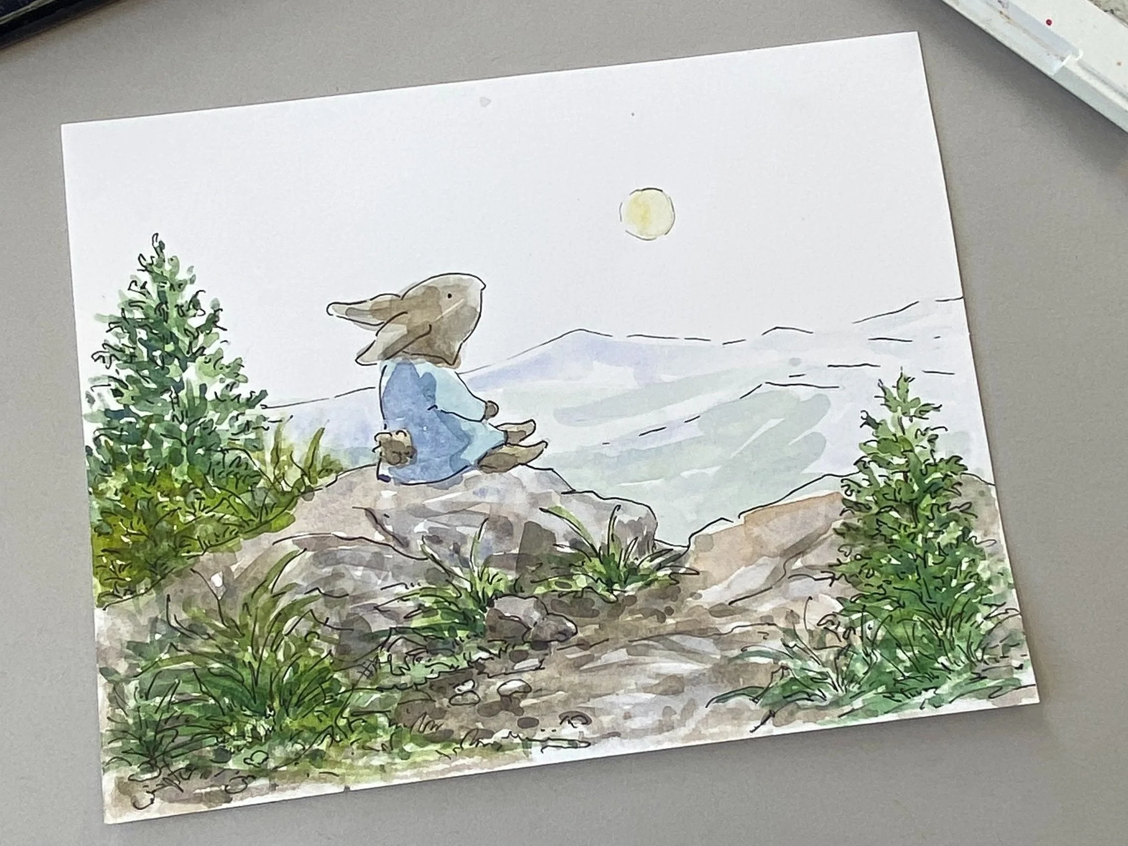 Watercolor of a rabbit sitting on a mountain top looking at the moon.