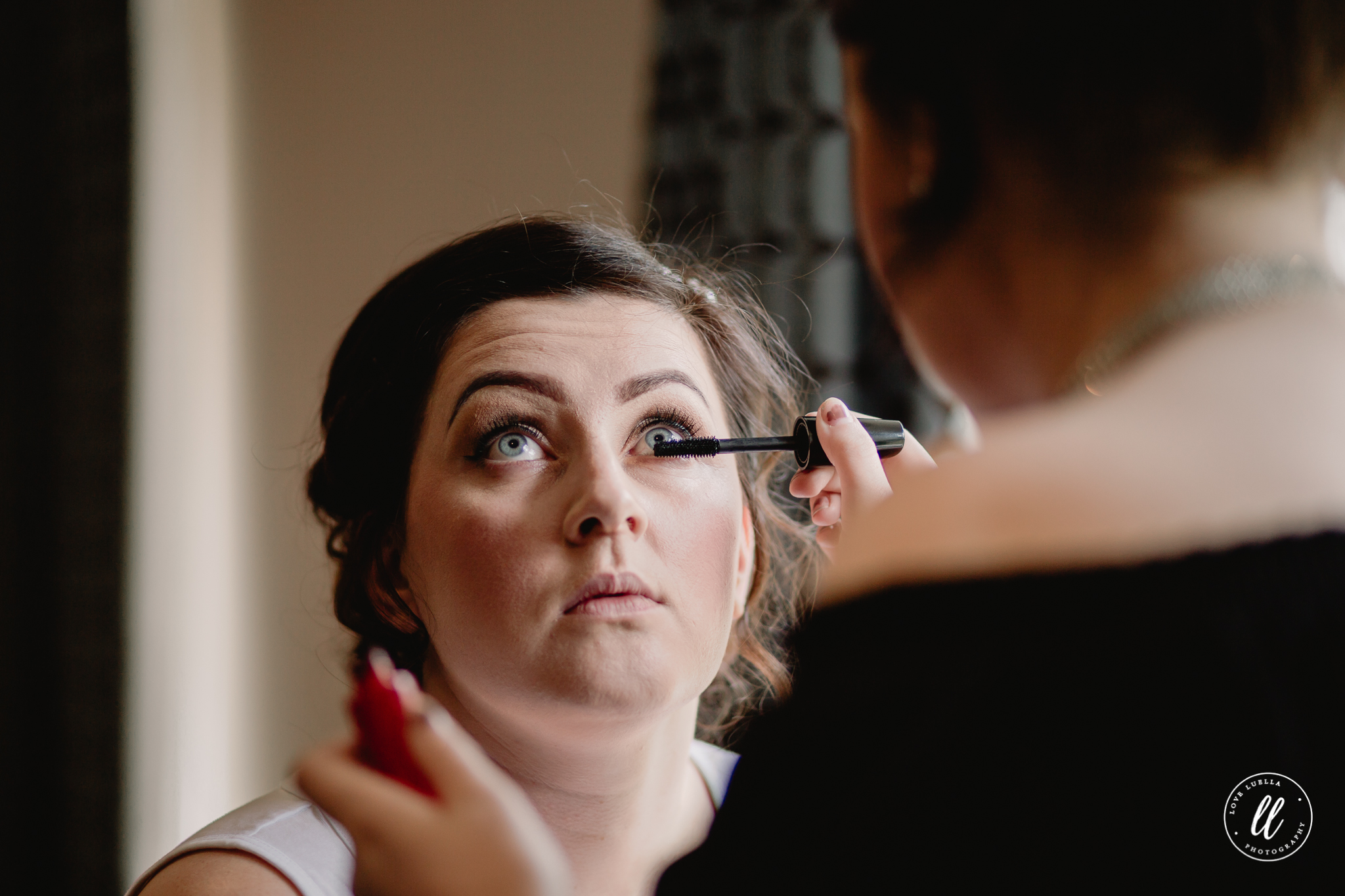Mascara being applied to the bride near a window at The Kinmel