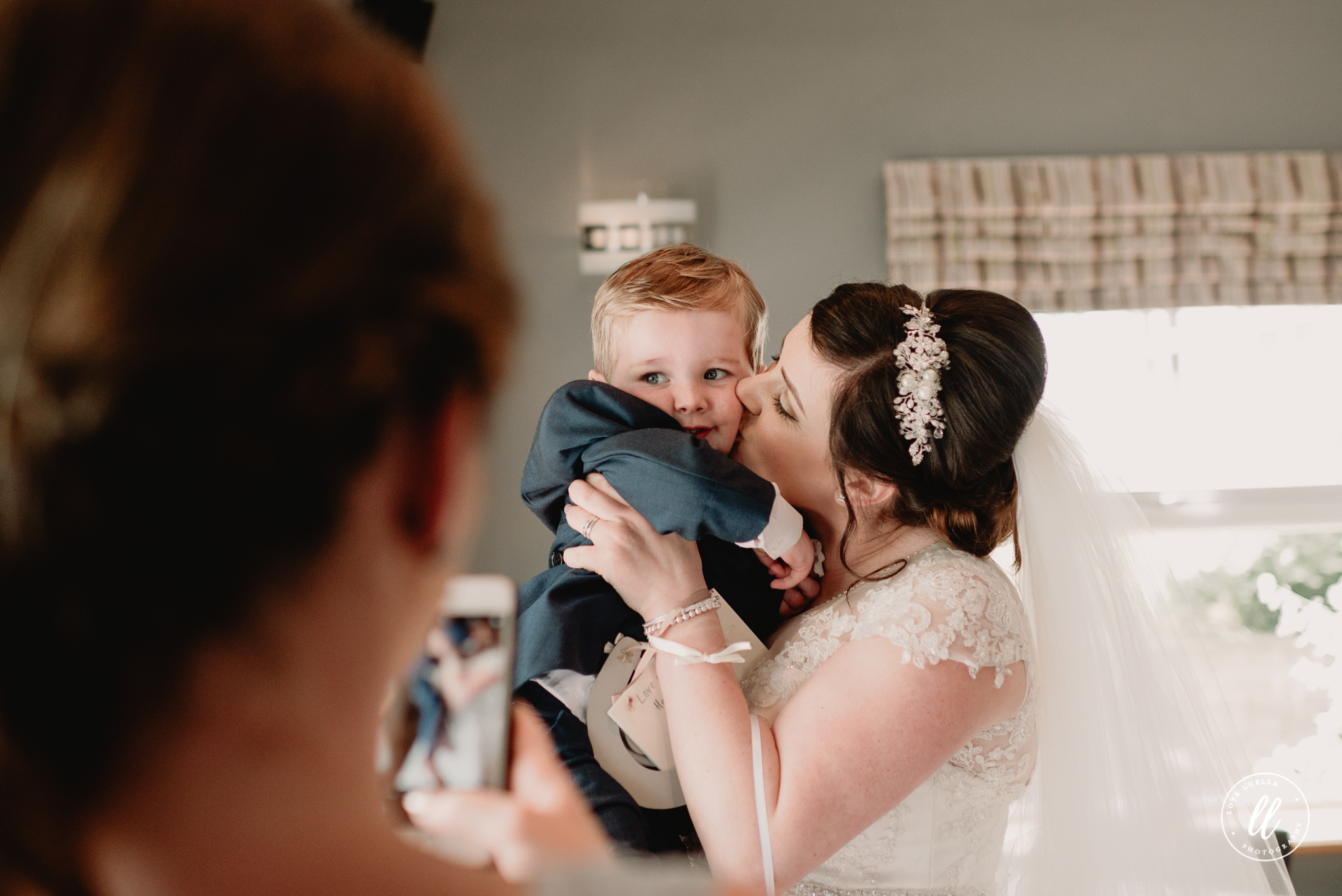 The bride holding her good friends baby and giving him a kiss