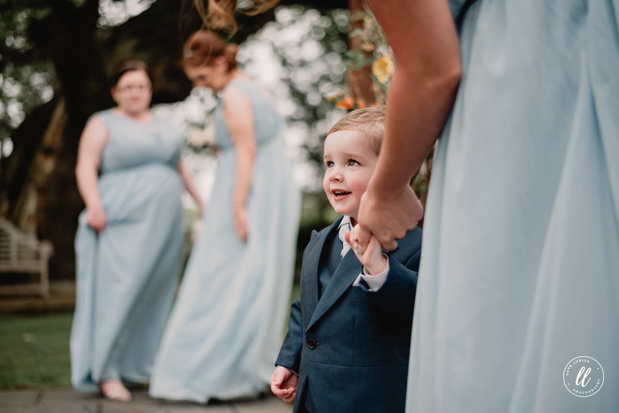 A natural portrait of a young page boy holding his mothers hand
