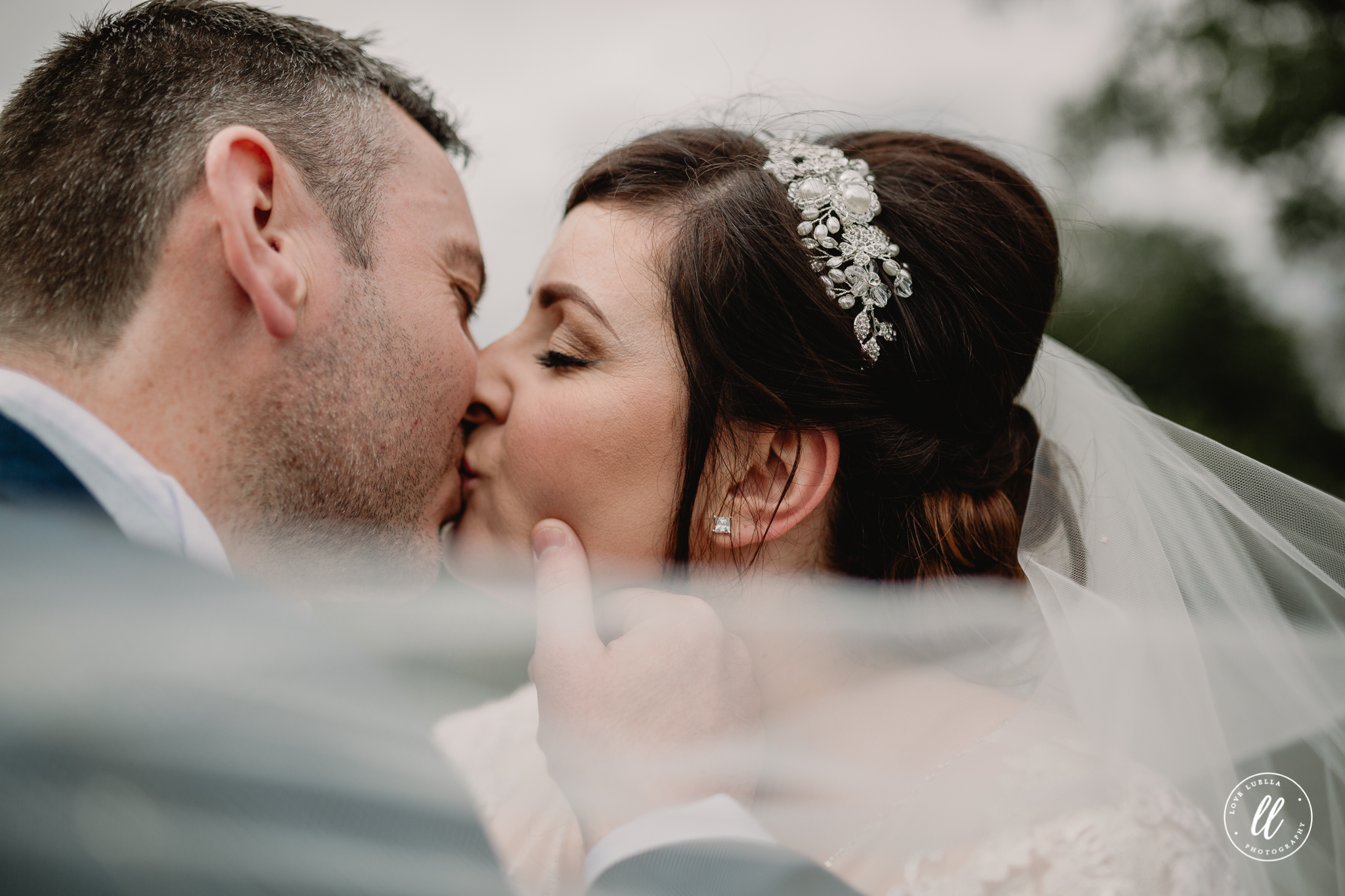 the bride and groom kissing, the grooms thumb resting on the brides cheek