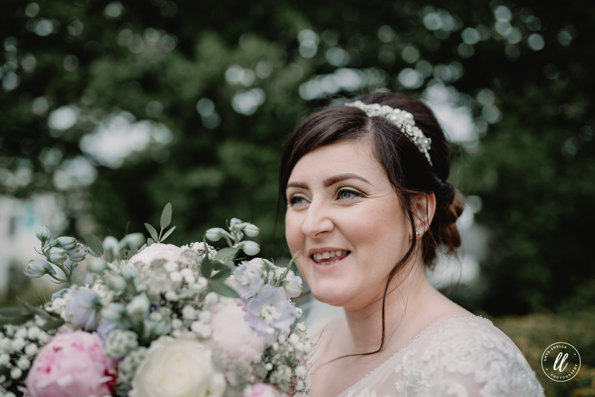 The bride laughing holding her bouquet close to her face