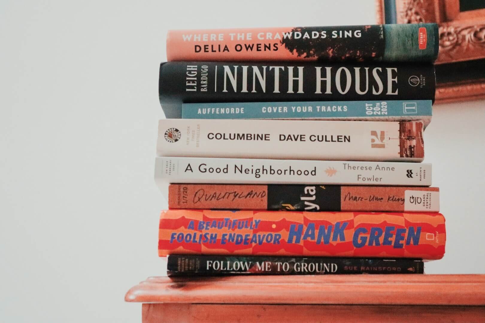 A stack of 2020 books: Where the Crawdads Sing by Delia Owens, Ninth House by Leigh Bardugo, Cover Your Tracks by Daco Auffenorde, Columbine by Dave Cullen, A Good Neighborhood by Therese Anne Fowler, Qualityland by Marc-Uwe Kling, A Beautifully Foo…