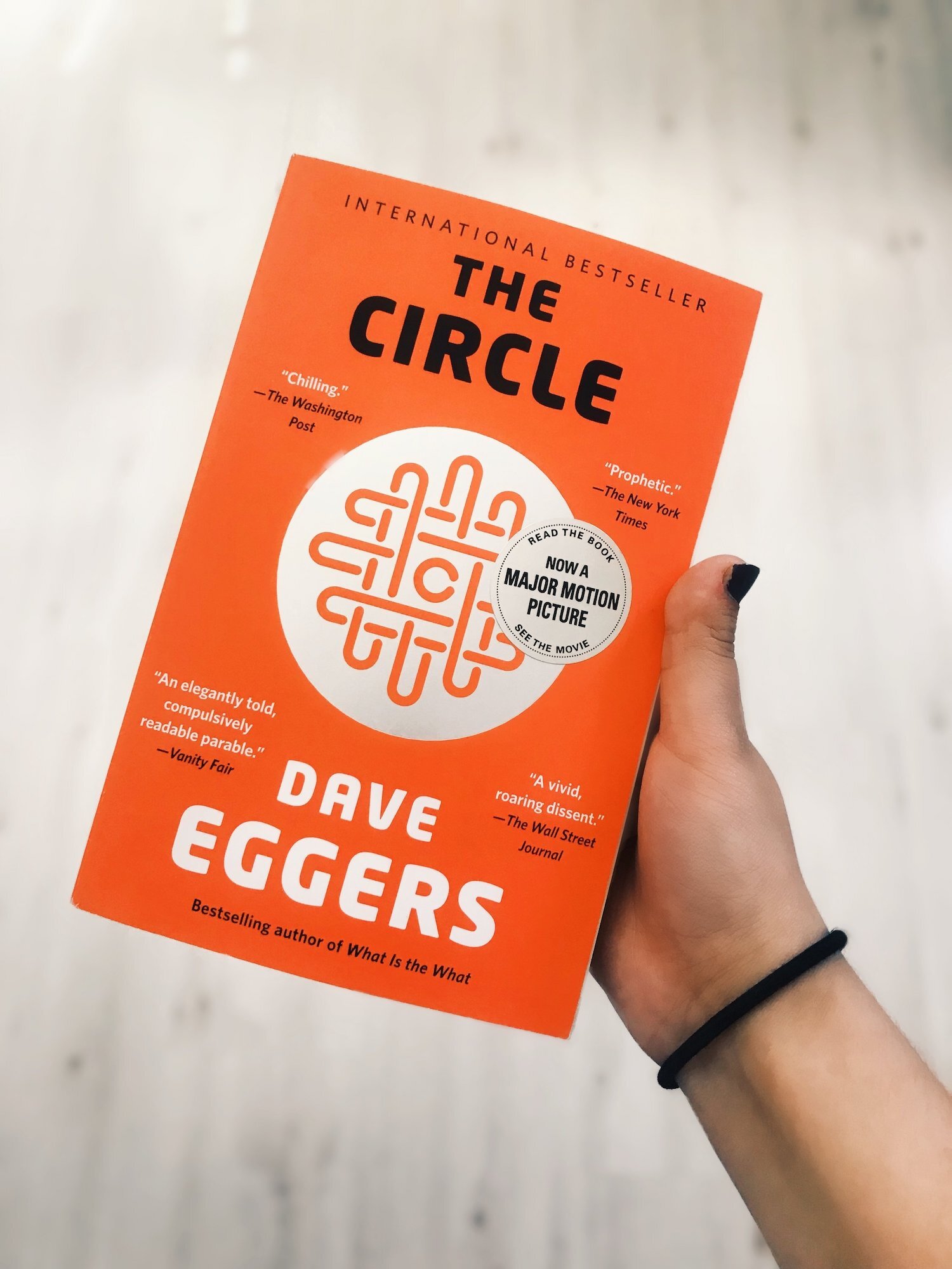 A copy of The Circle by Dave Eggers held in a hand.