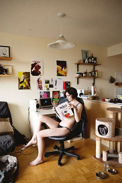 Rossi in her workspace, surrounded by artwork created by her friends. She reads The Nao of Brown by Glyn Dillon.