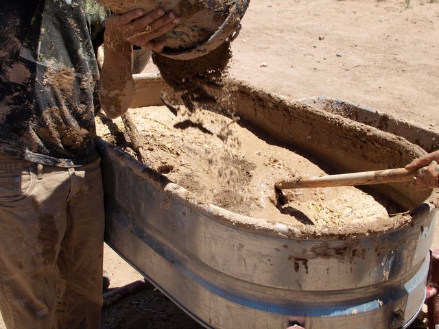 Volunteers mixing an adobe block mix for a community project.