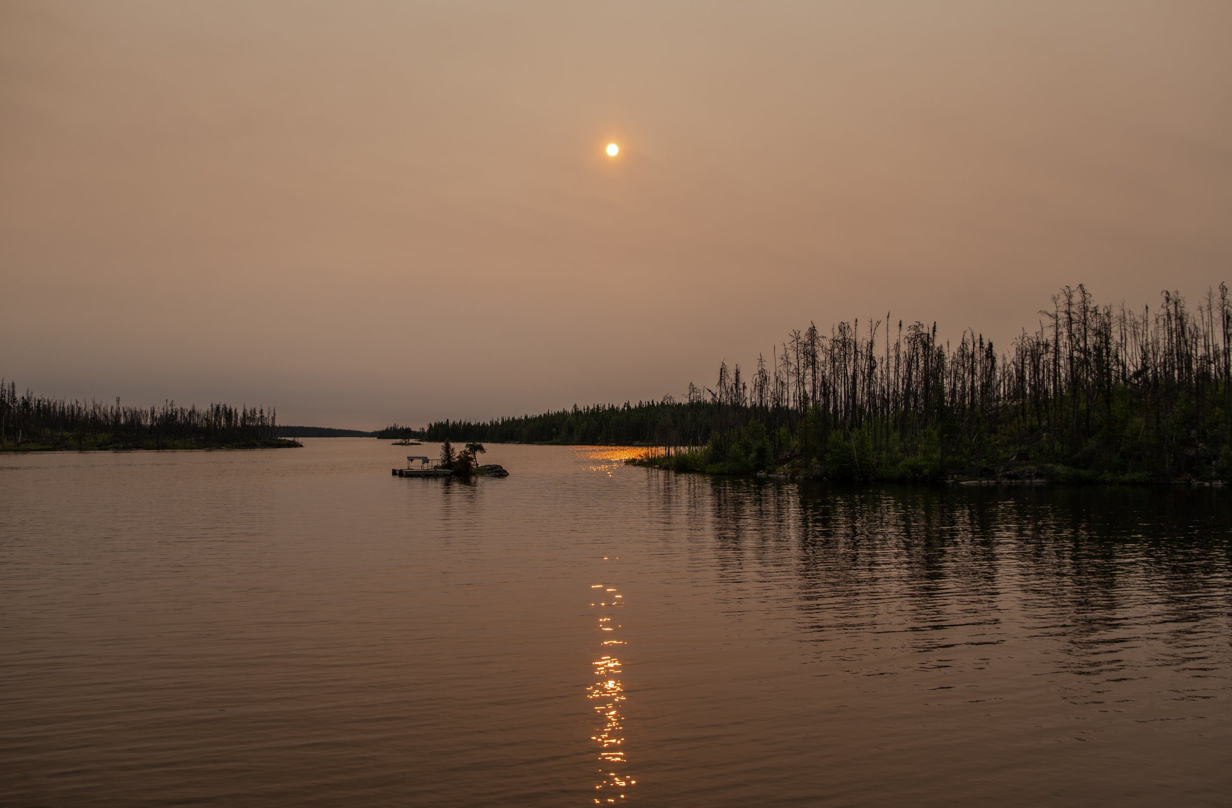  Early morning sunrise over the bay at Grayling Lodge. The orange sun is burning it’s way through the thick smoke from surrounding forest fires.  
