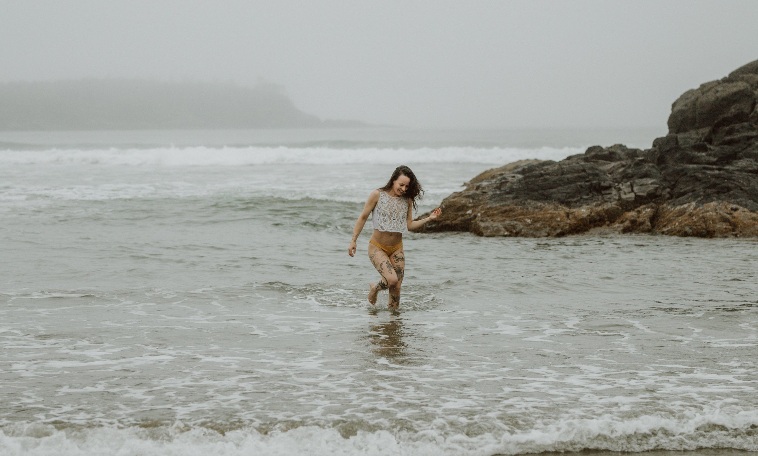  Surfer Emily Ballard walking in the ocean at the pacific Sands Tofino B.C. 