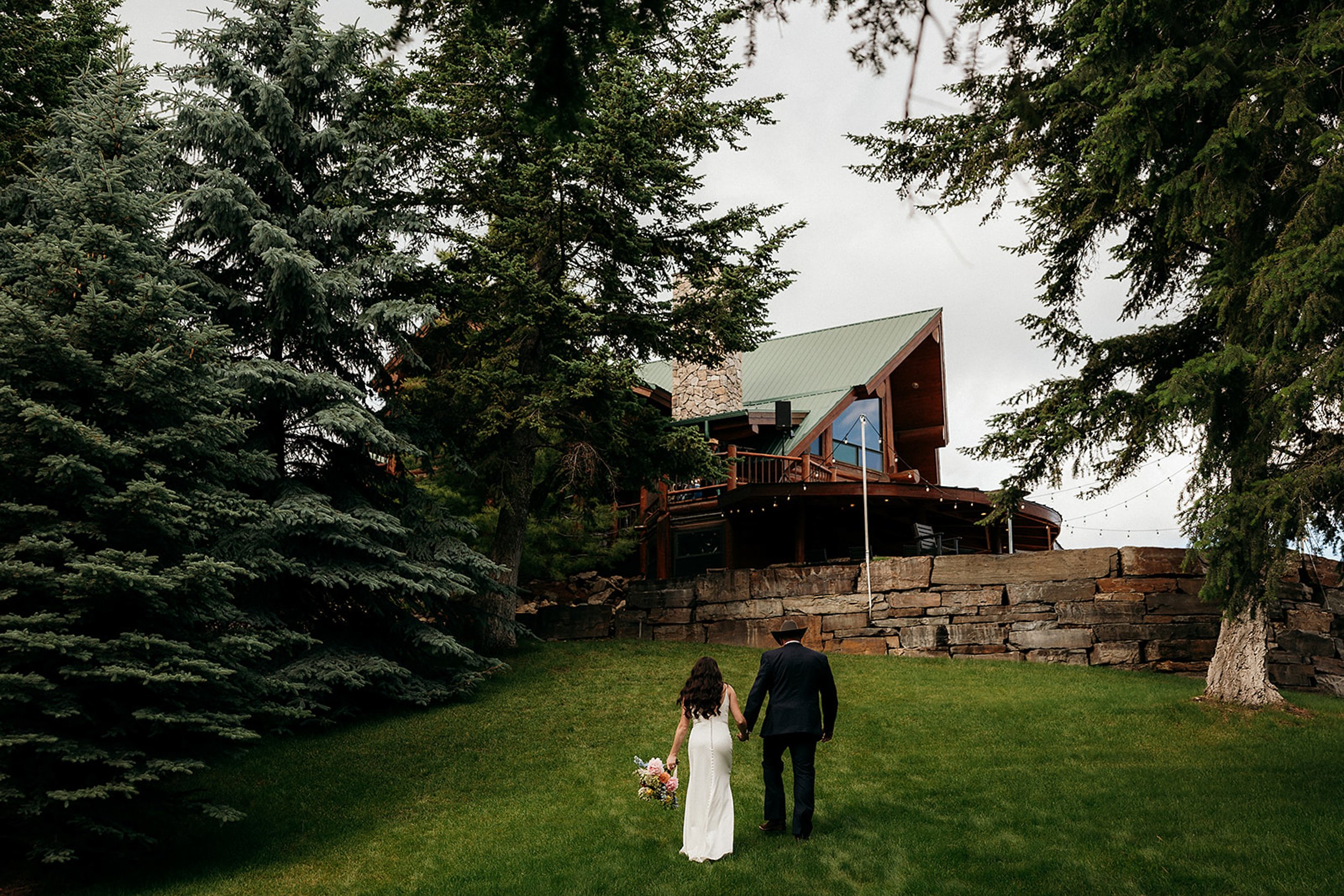 bride and groom walk up hill to ridge at flathead lake wedding venue