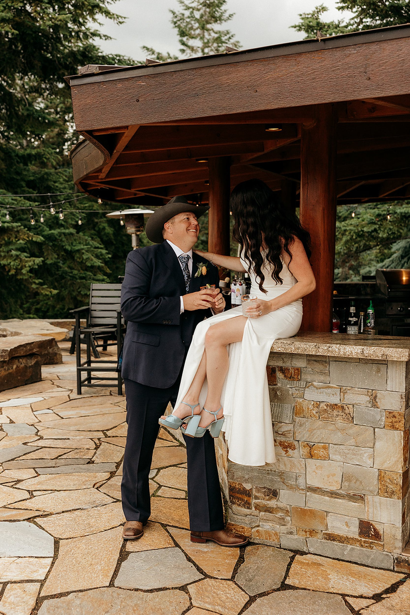 bride and groom hold drinks and smile at each other