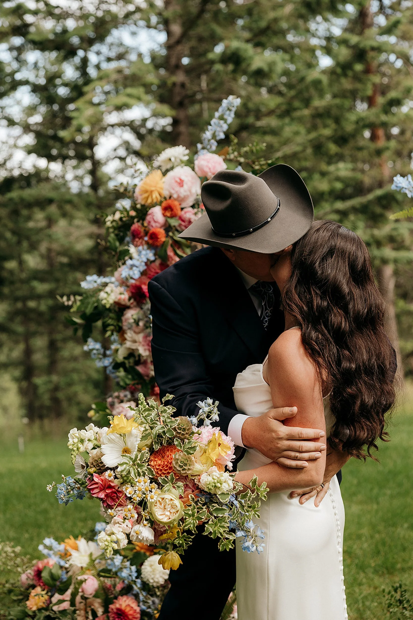 bride and groom kiss at altar with flowers