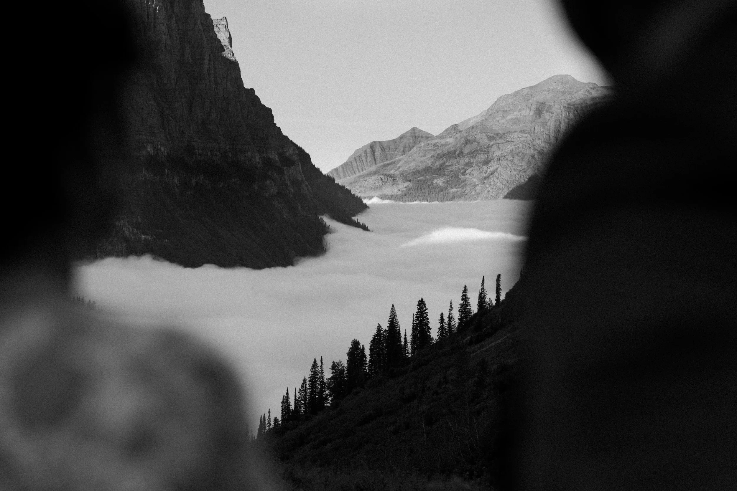 Socked in fog under mountains at Big Bend In Glacier National Park - black and white