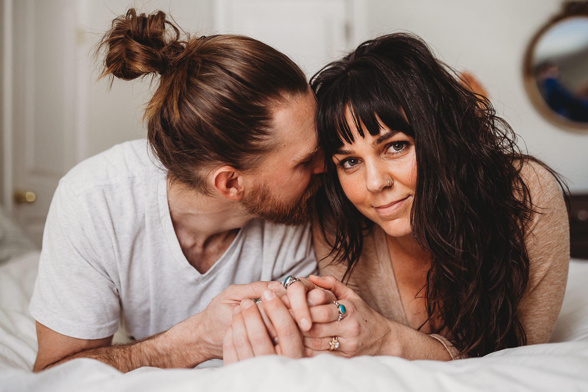 Couple lay on bed during in-home engagement photo session by RaeEllen Photography in New Hampshire