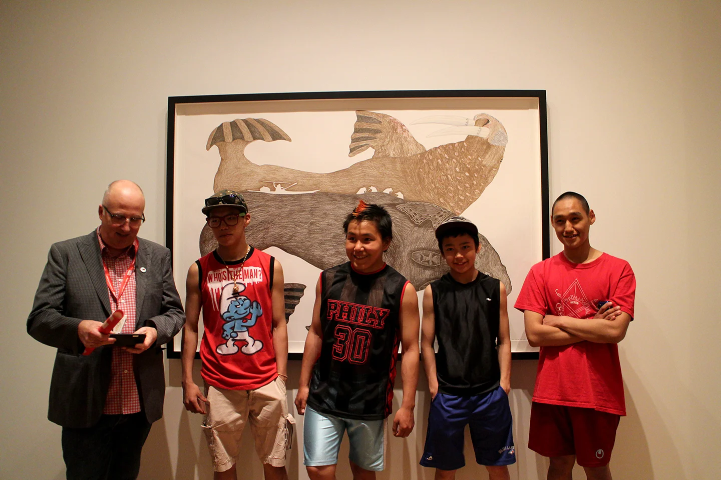 Andrew Hunter from the Art Gallery of Ontario poses with the youth in front of a drawing by Tim Pitsiulak. Photo by Alexa Hatanaka.