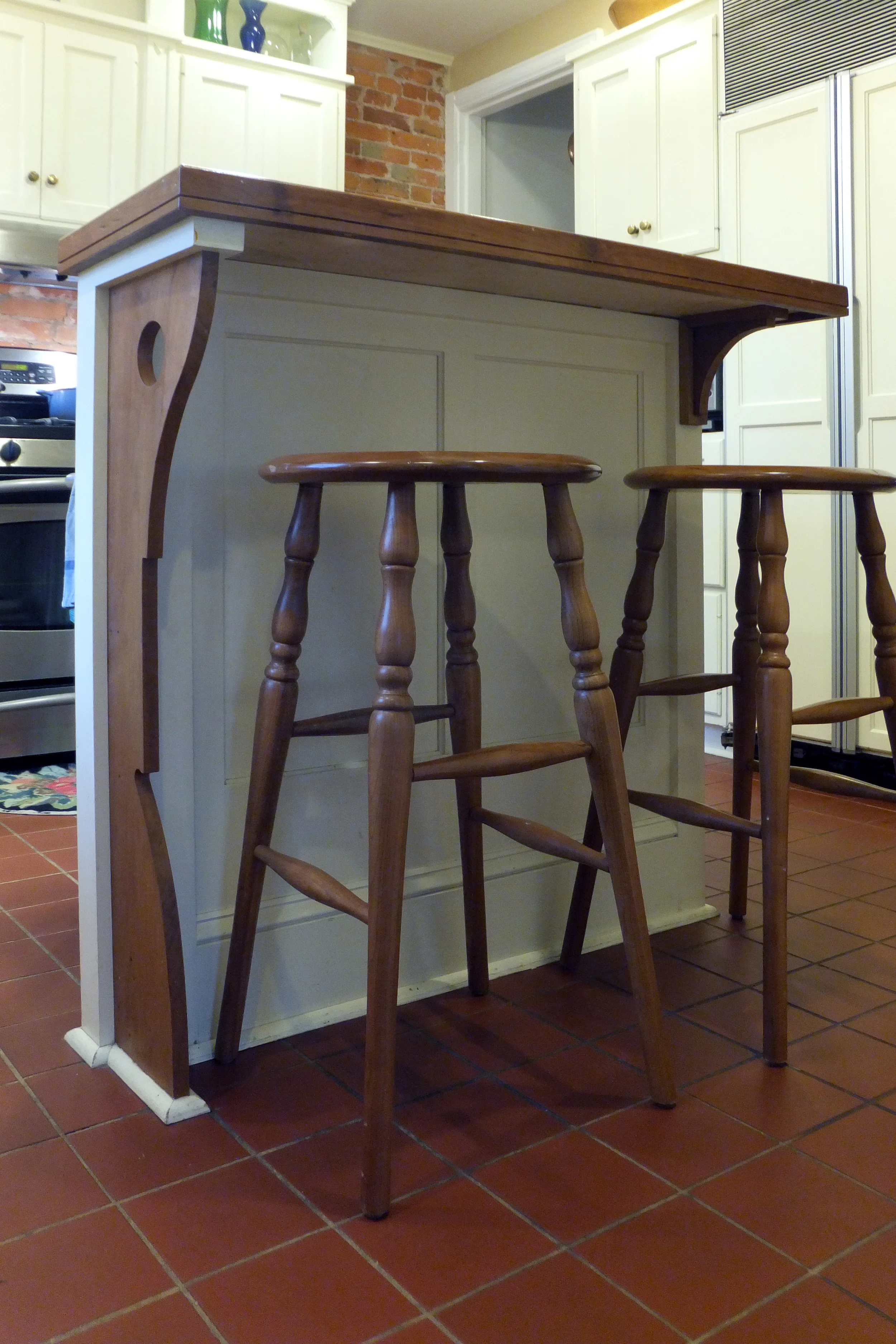  The island features custom cherry wood brackets and countertop. Salvaged cabinet panels front the island. 