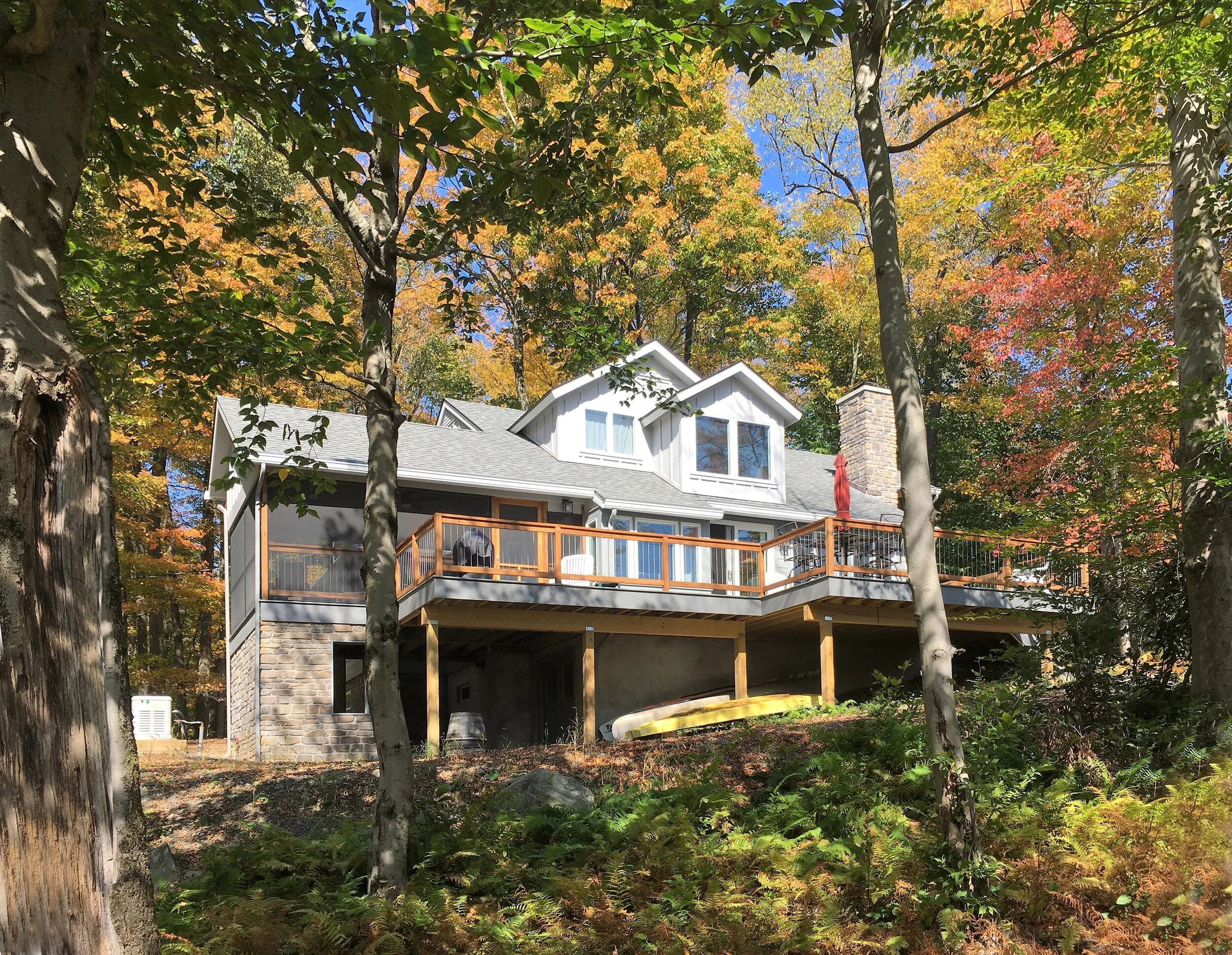  The lake-facing facade. The screened porch to the left was expanded by about 8’ and features a stone-clad foundation and storage shed area underneath.  