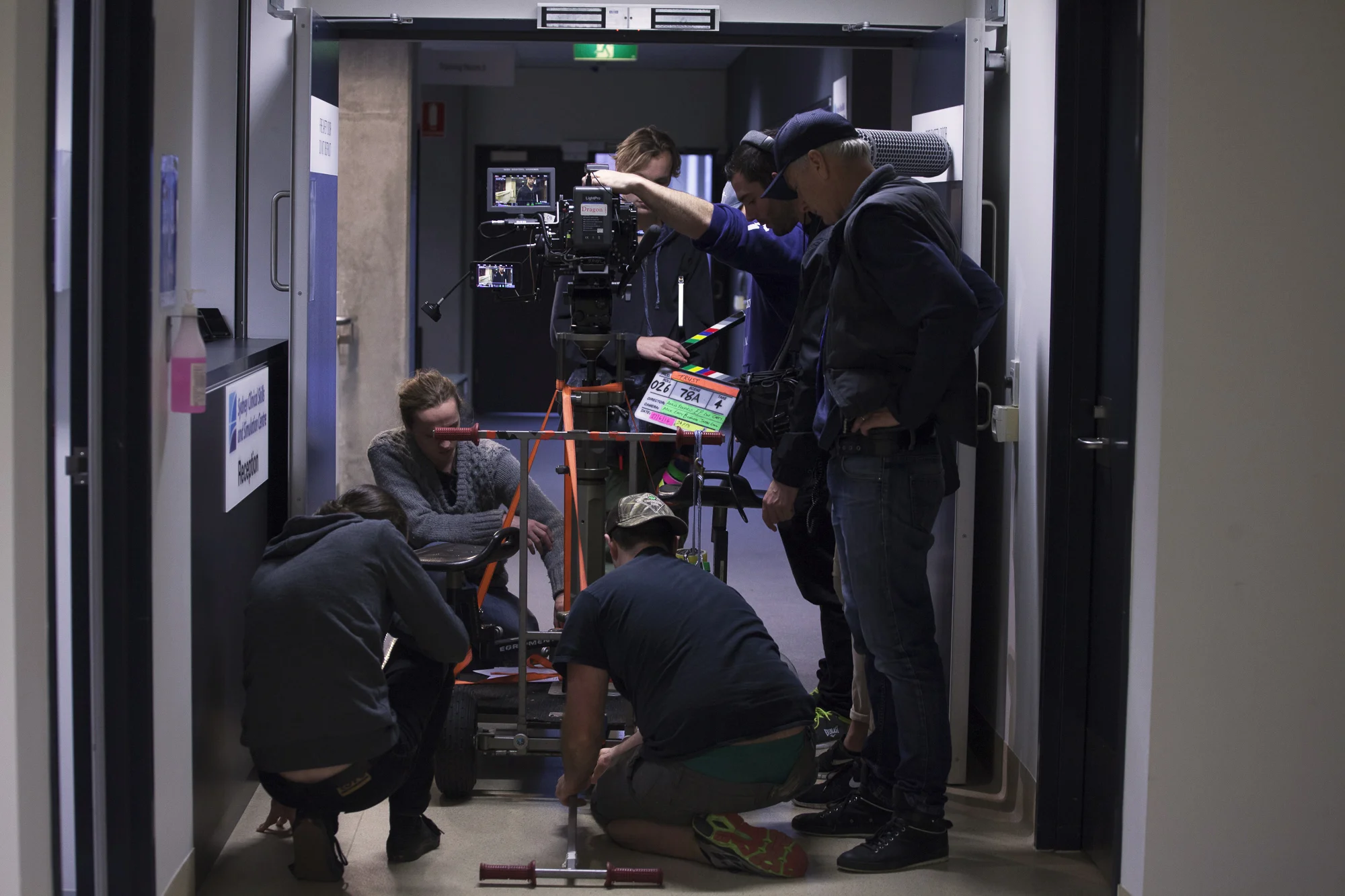 Our grips department responsible for making sure the camera moves without any problems. The crew here are securing a dolly in this picture before it is about to be run down the hallway.