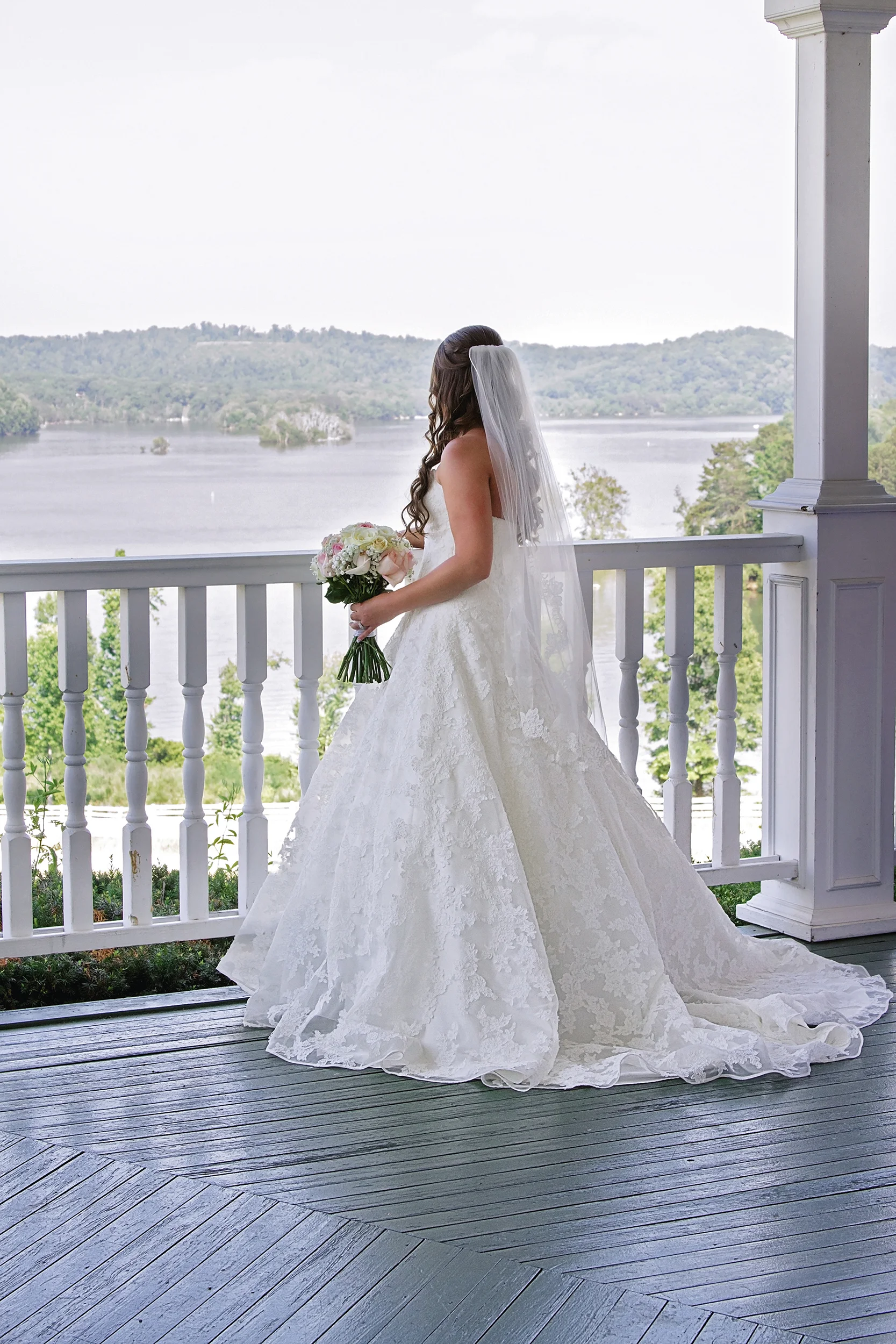 Bride on porch looking at mountains and lake