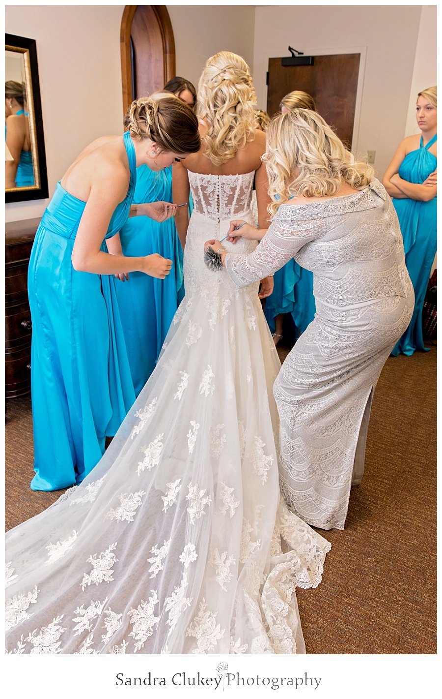 Mom helping bride with final touches on dress