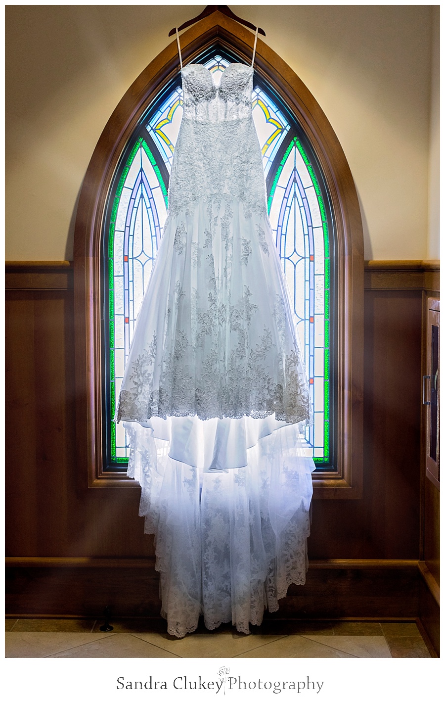 Gorgeous wedding gown by stained glass window