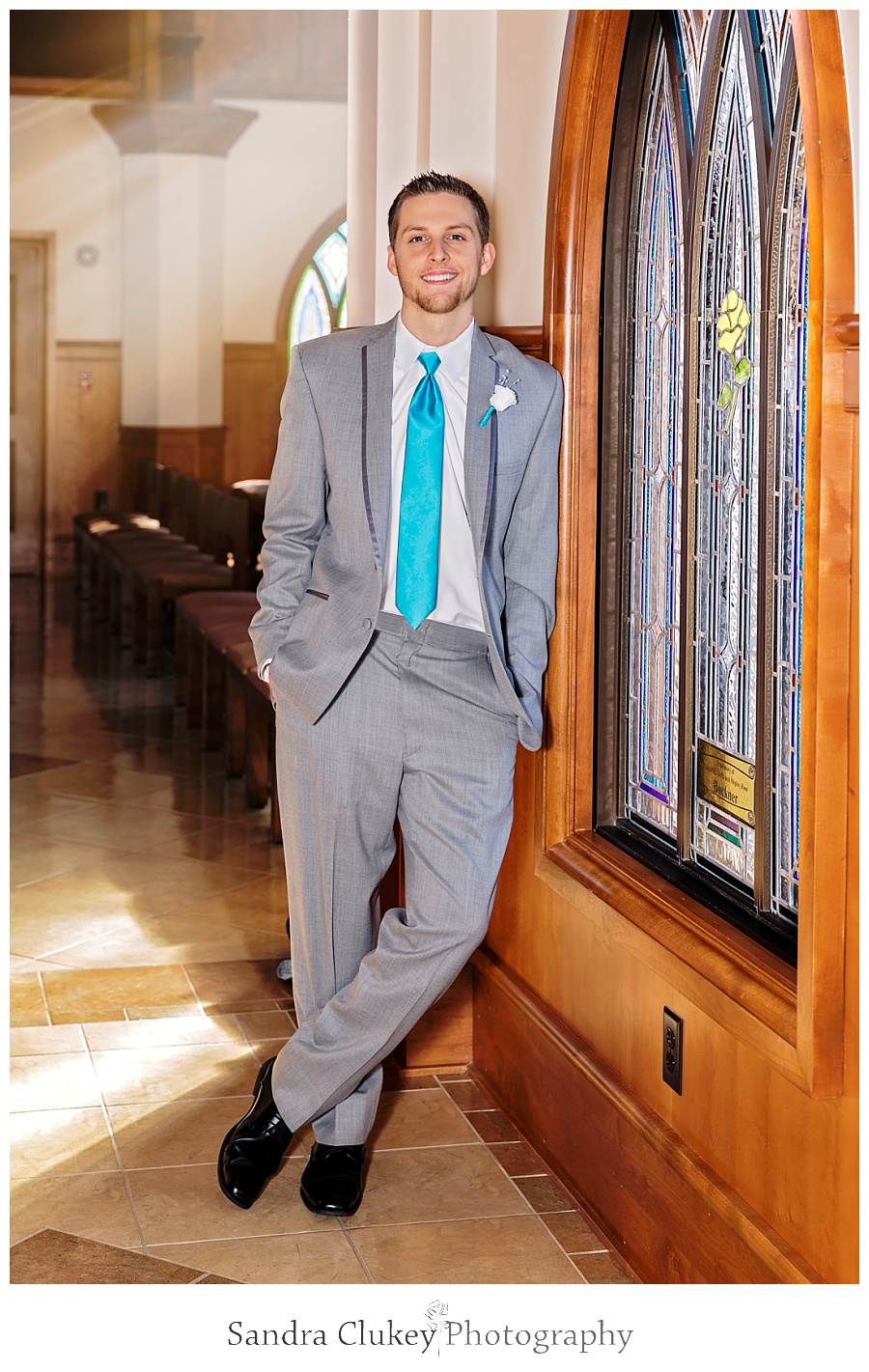 Groom by stained glass chapel windows