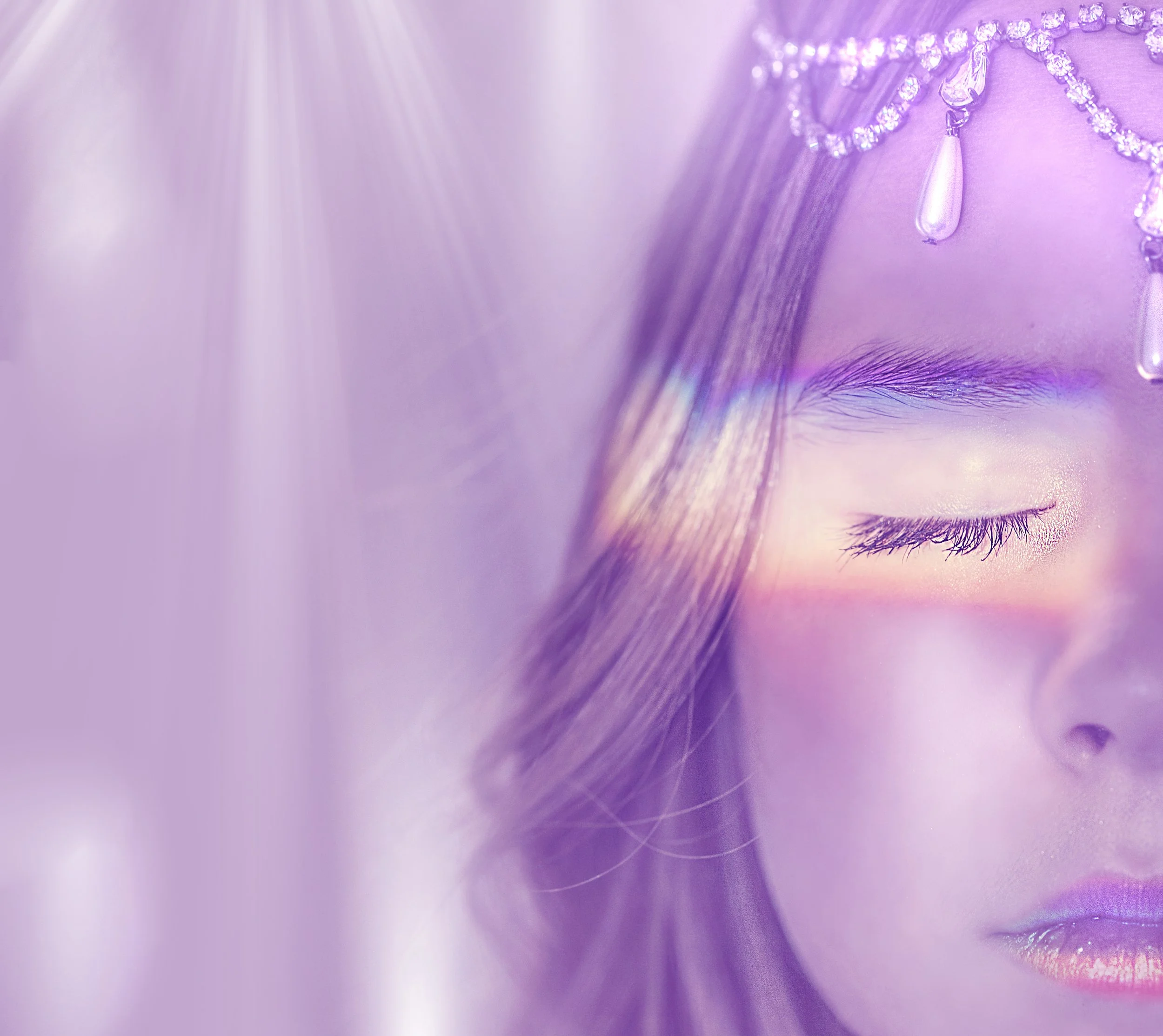 Close-up of a person's eye with purple makeup, wearing a purple beaded and rhinestone necklace with teardrop-shaped pendants.