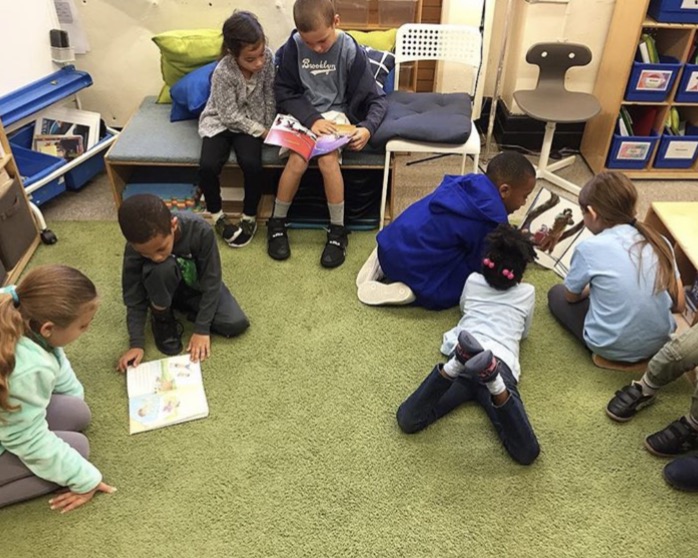Kindergarten and 3rd grade buddies reading together. 