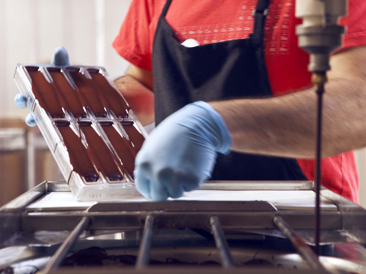  Dispensed chocolate is distributed evenly in the molds with a vibrating table. 