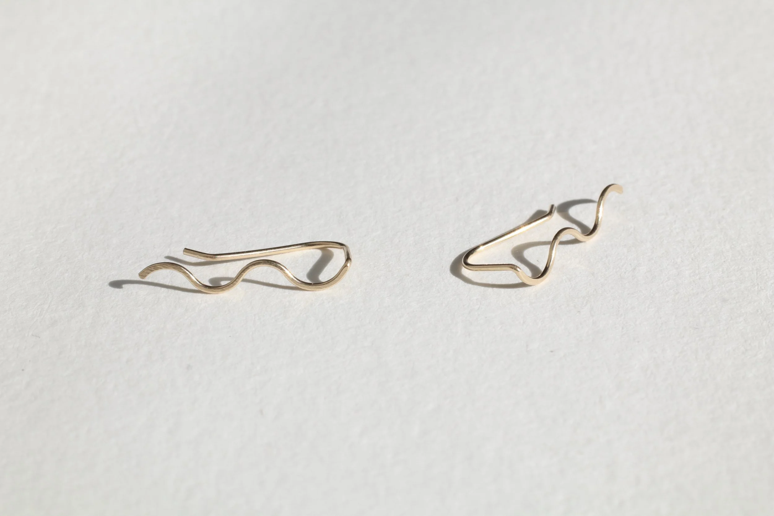 gold squiggle ear climbers on white with shadow.JPG