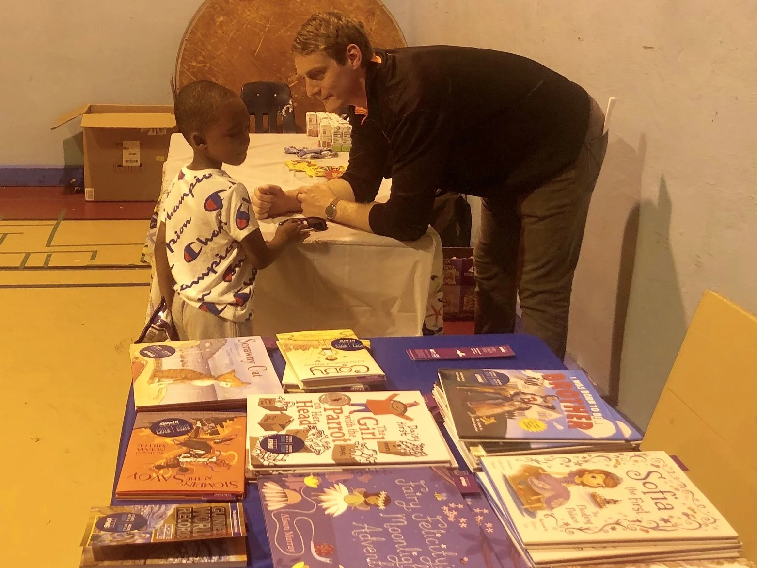 a kpmg employee helps a cyc child pick a new book.