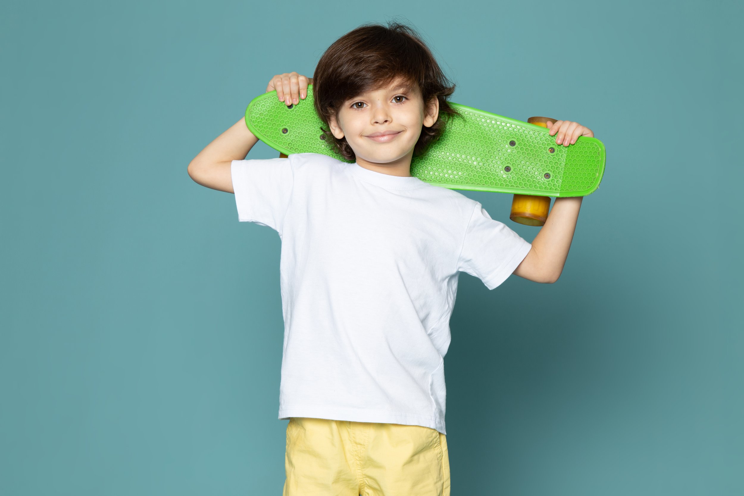 front-view-smiling-cute-kid-white-t-shirt-holding-skateboard-blue-floor.jpg