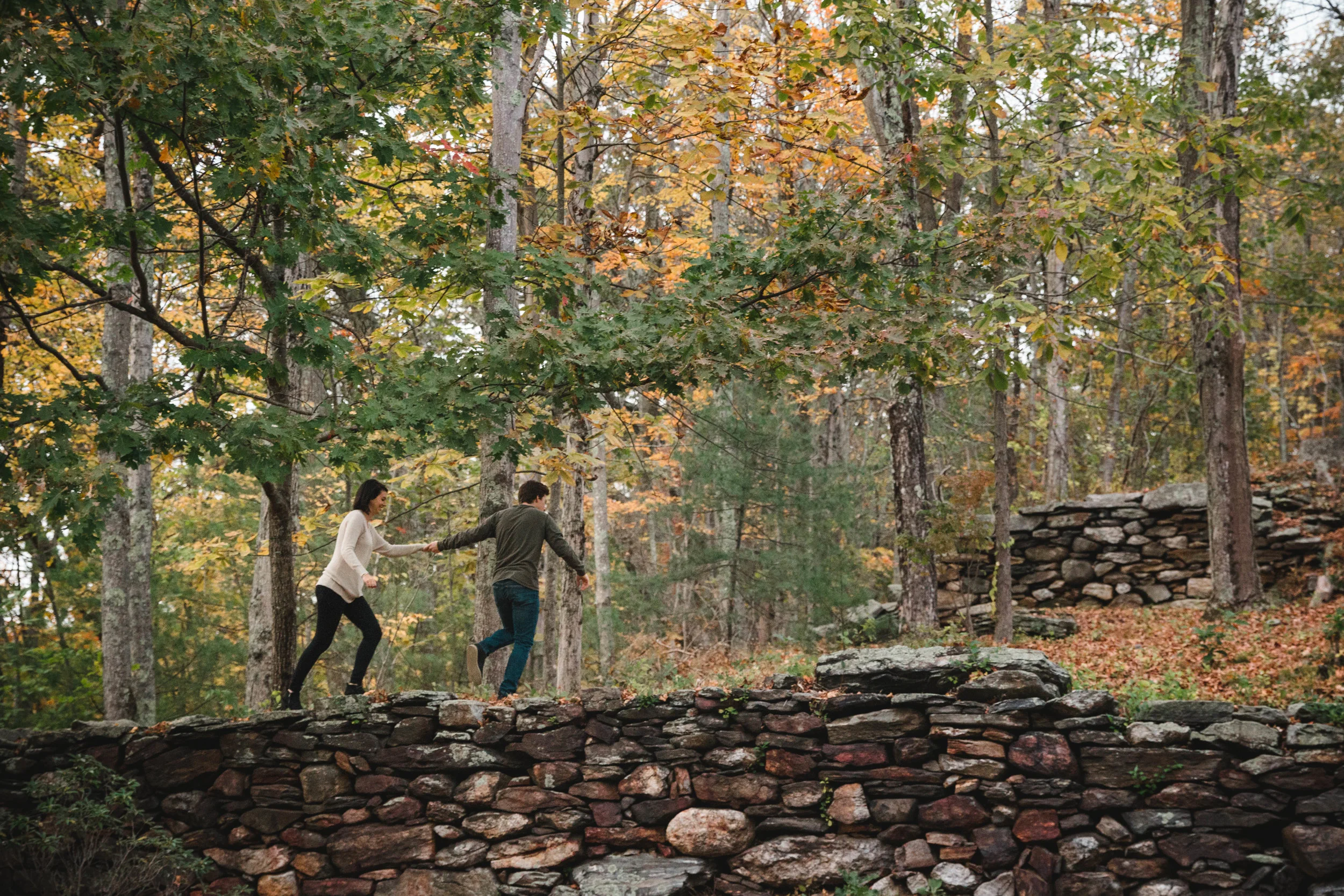 couple running into the woods with fall foliage