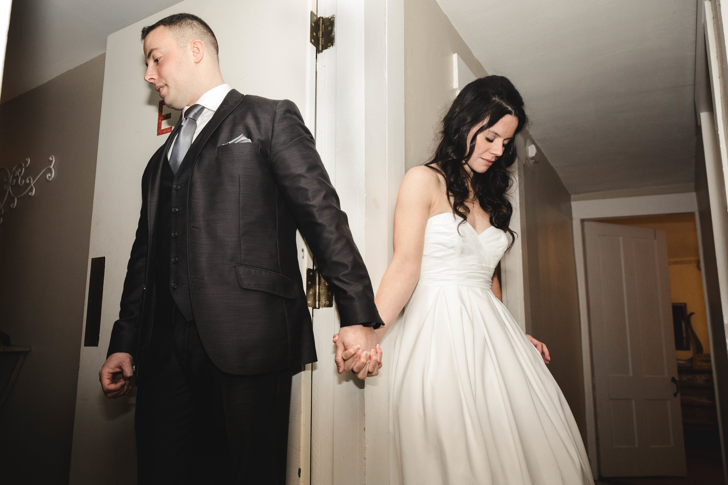 bride and groom praying around corner before ceremony