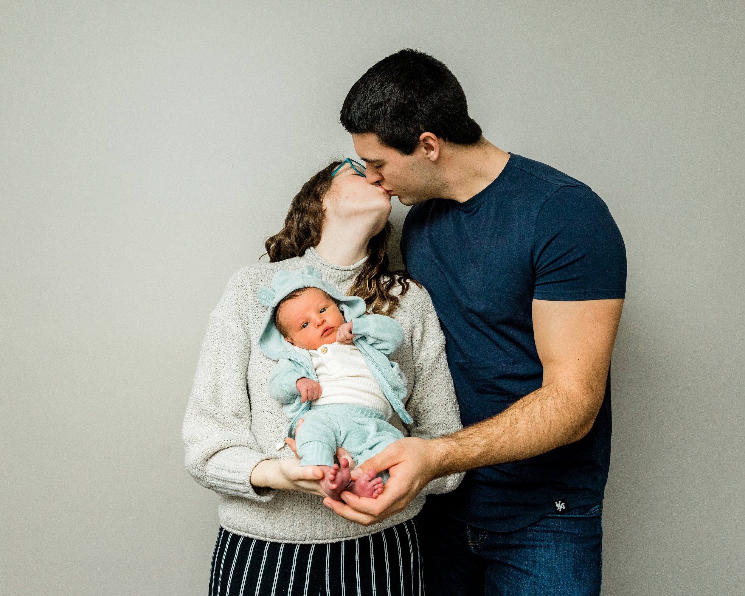 Mom &amp; dad holding newborn and kissing