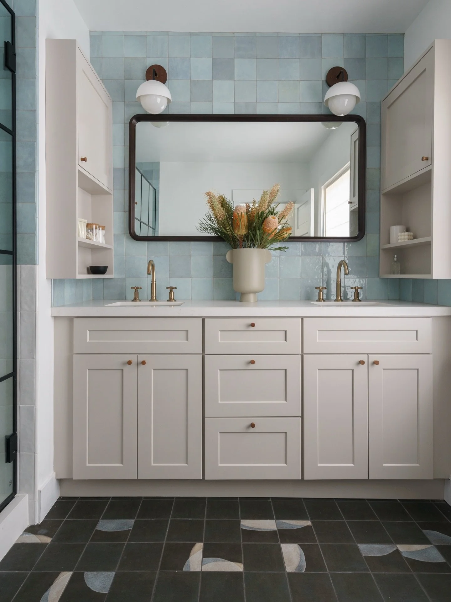 Soothing blue and tonal white tile wrap the walls in a color-block, while the darker &ldquo;random&rdquo; patterned floor grounds the space with movement and depth. It&rsquo;s playful but polished and all the proof to show that bathrooms can be both 