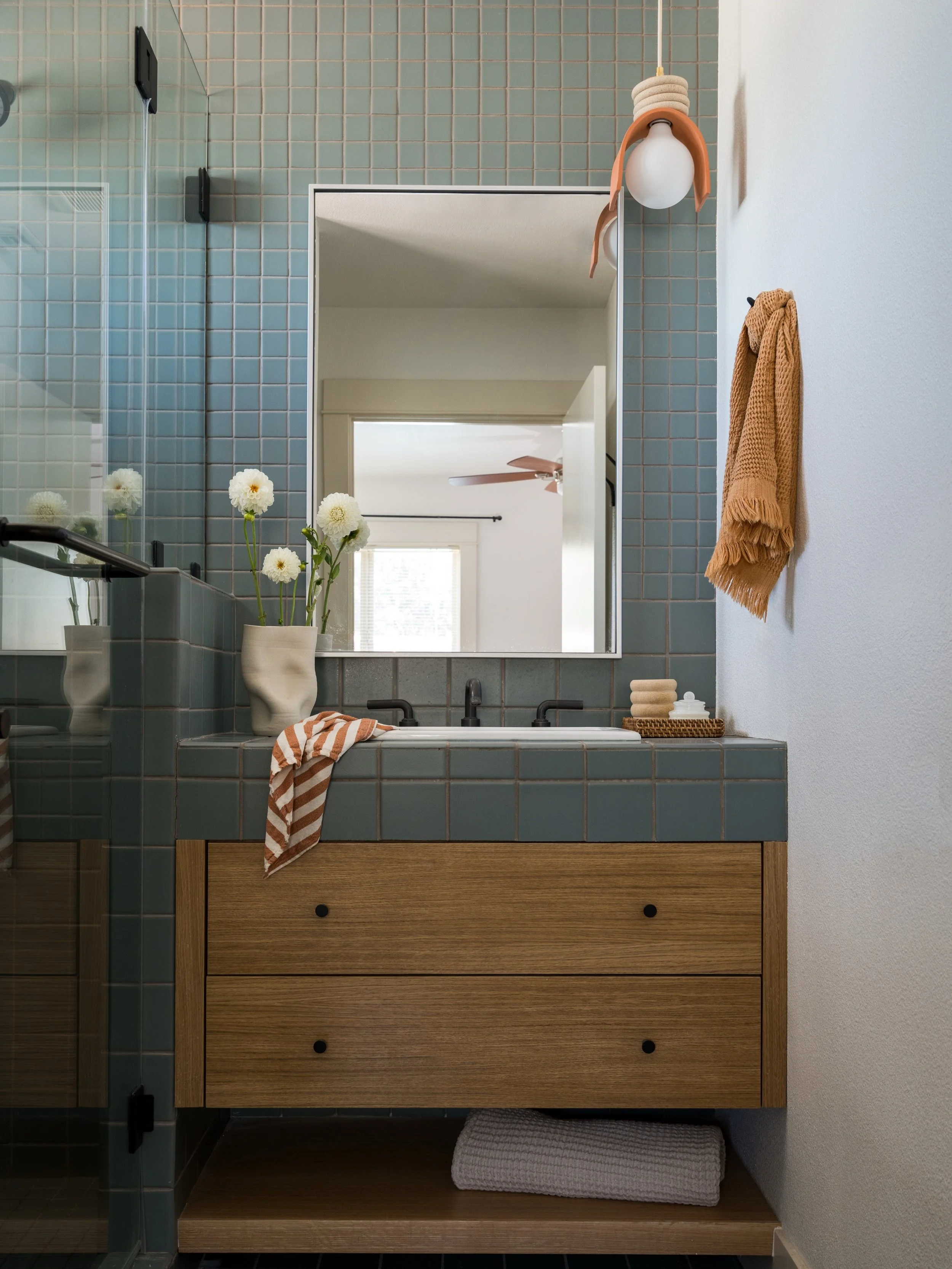A lesson in intentional restraint: We used the same tile glaze throughout the bathroom (walls, floors, + countertop) while playing with different square sizes. Then layered in warm white oak, dark bronze, and rust-hued accents for an overall calming 