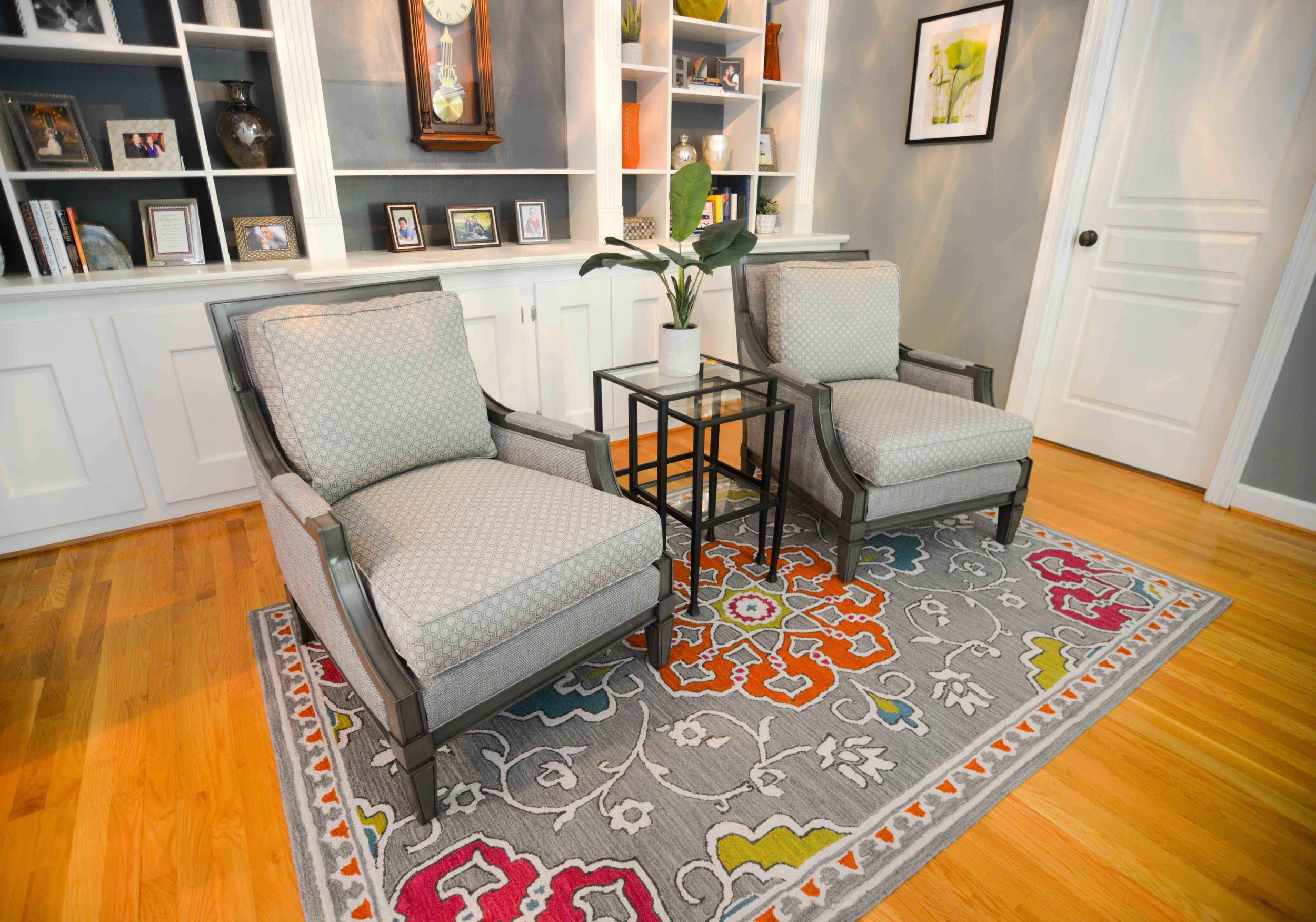 Library seating area featuring upholstered gray arm chairs and colorful rug by NC Lake Norman interior designer, 180 Spaces.