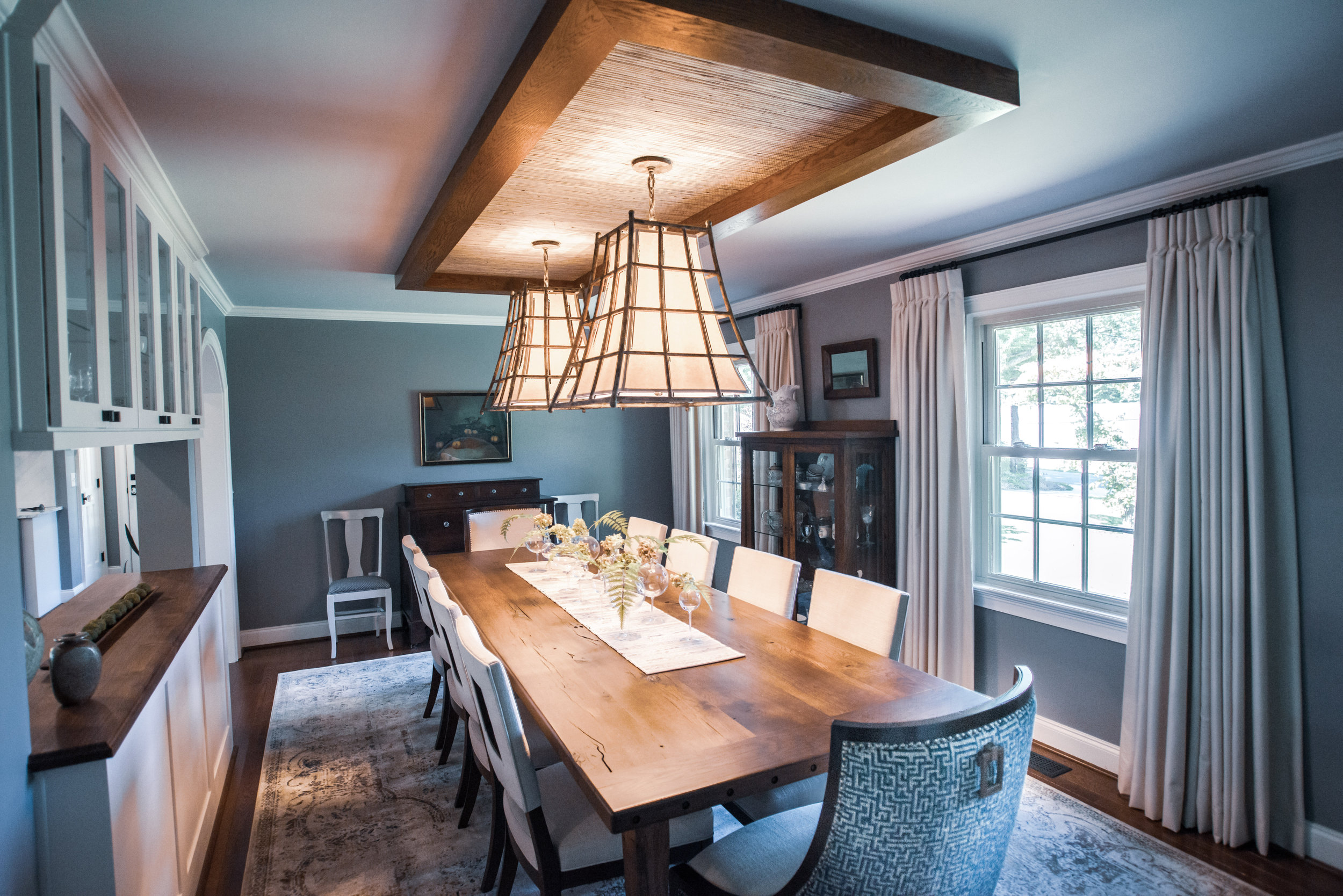 Farmhouse style dining room remodel featuring a custom table for 10, cedar wrapped beams and grasscloth &amp; 2 forged chandeliers  by 180 Spaces, Interior Design | Lake Norman NC