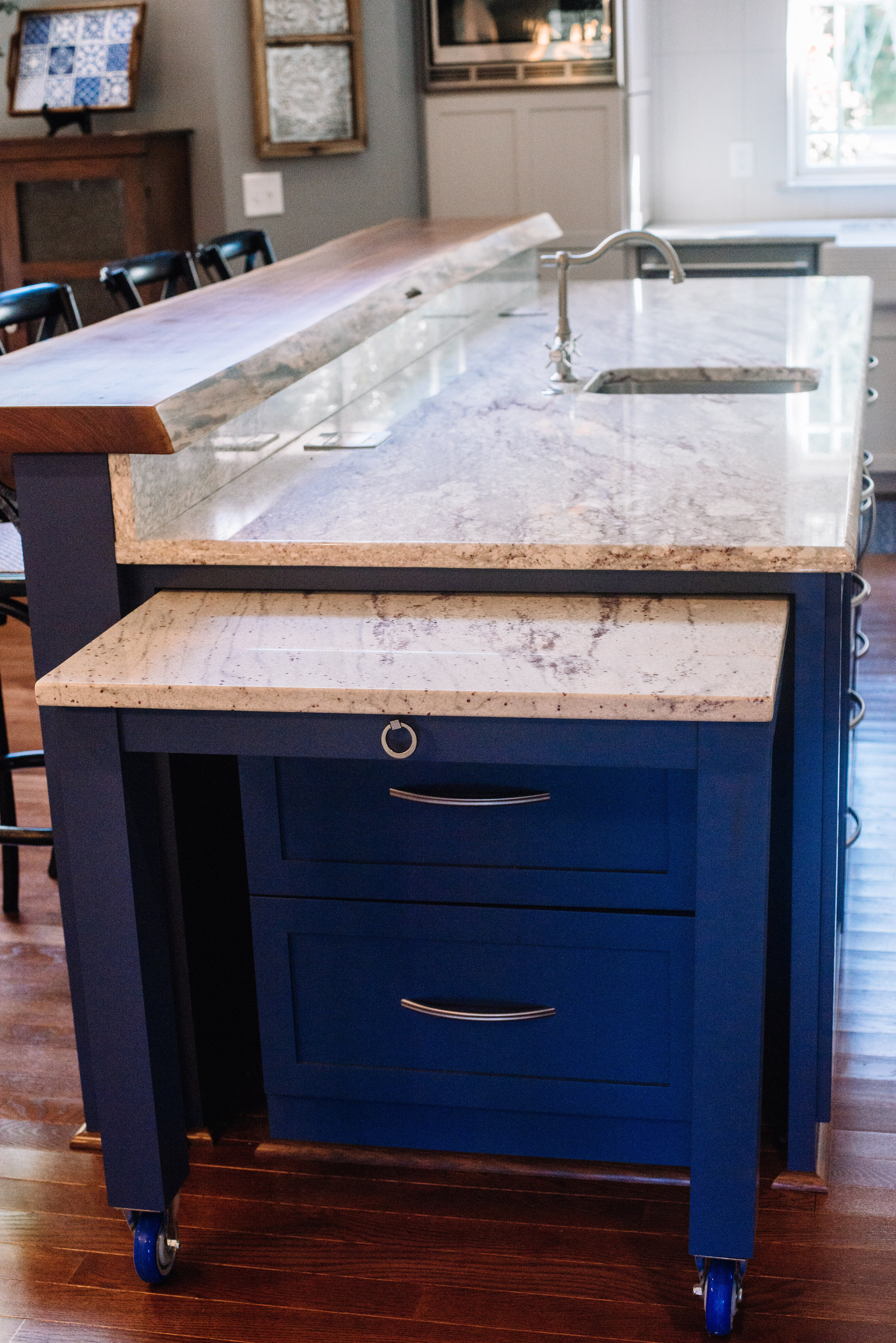 A clean white and blue kitchen design with large island and pull out work station by NC Lake Norman interior designer, 180 Spaces.