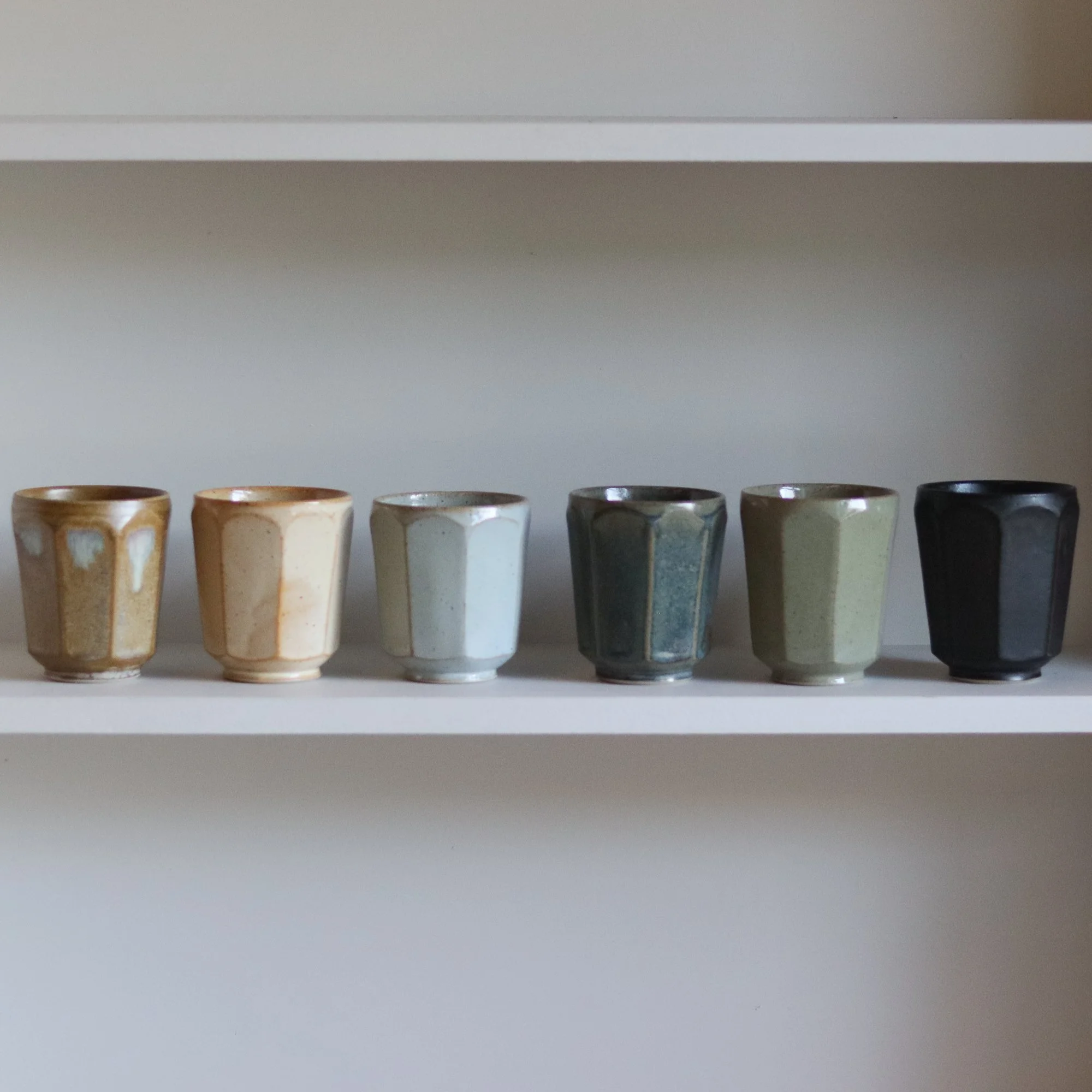 Row of stoneware faceted beakers by Pottery West